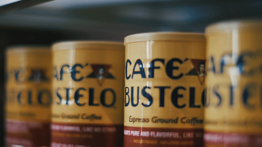 Close-up of cans of Cafe Bustelo espresso ground coffee on store shelf.