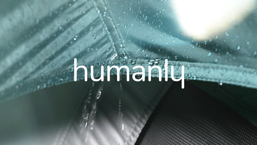 Close-up of a rain-covered, metallic surface with the word 'humanity' overlaid in white text.