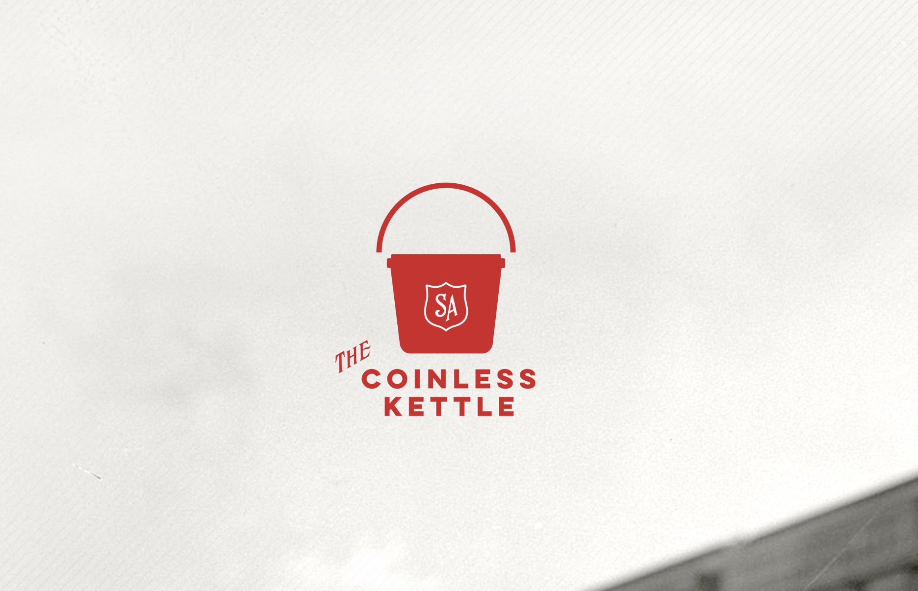 Red logo of a bucket with a handle, featuring a shield with the letters 'SA' and the text 'The Coinless Kettle' underneath.