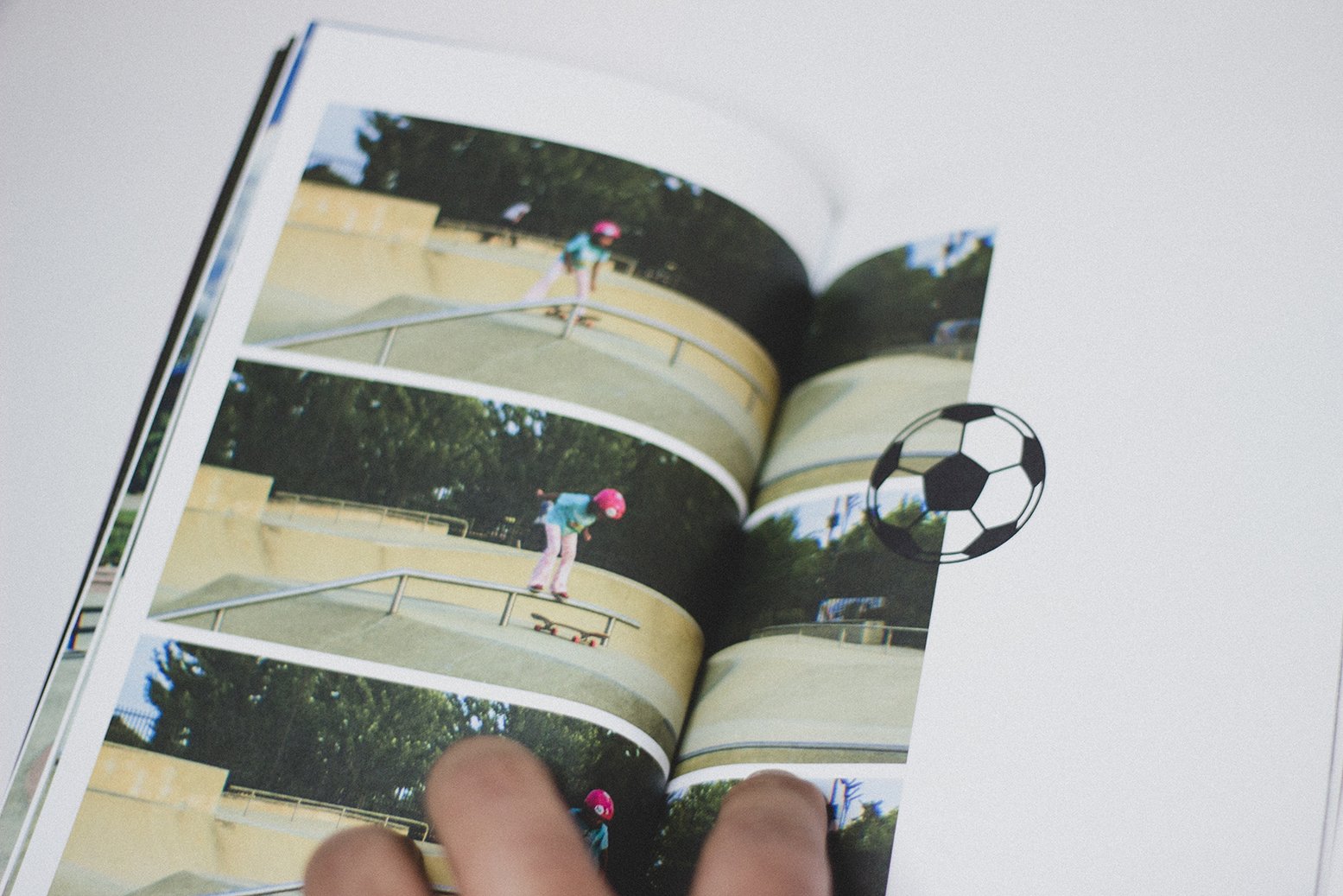 Open photo album displaying a sequence of four images of a young girl wearing a pink helmet and skateboard riding at a skatepark during daytime, with a football graphic overlay.