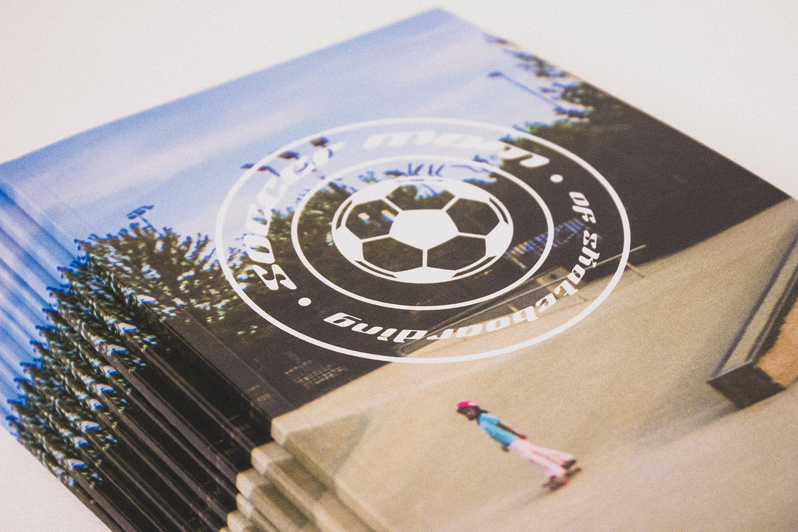 Stack of brochures or magazines with a soccer logo and a girl roller skating outside.