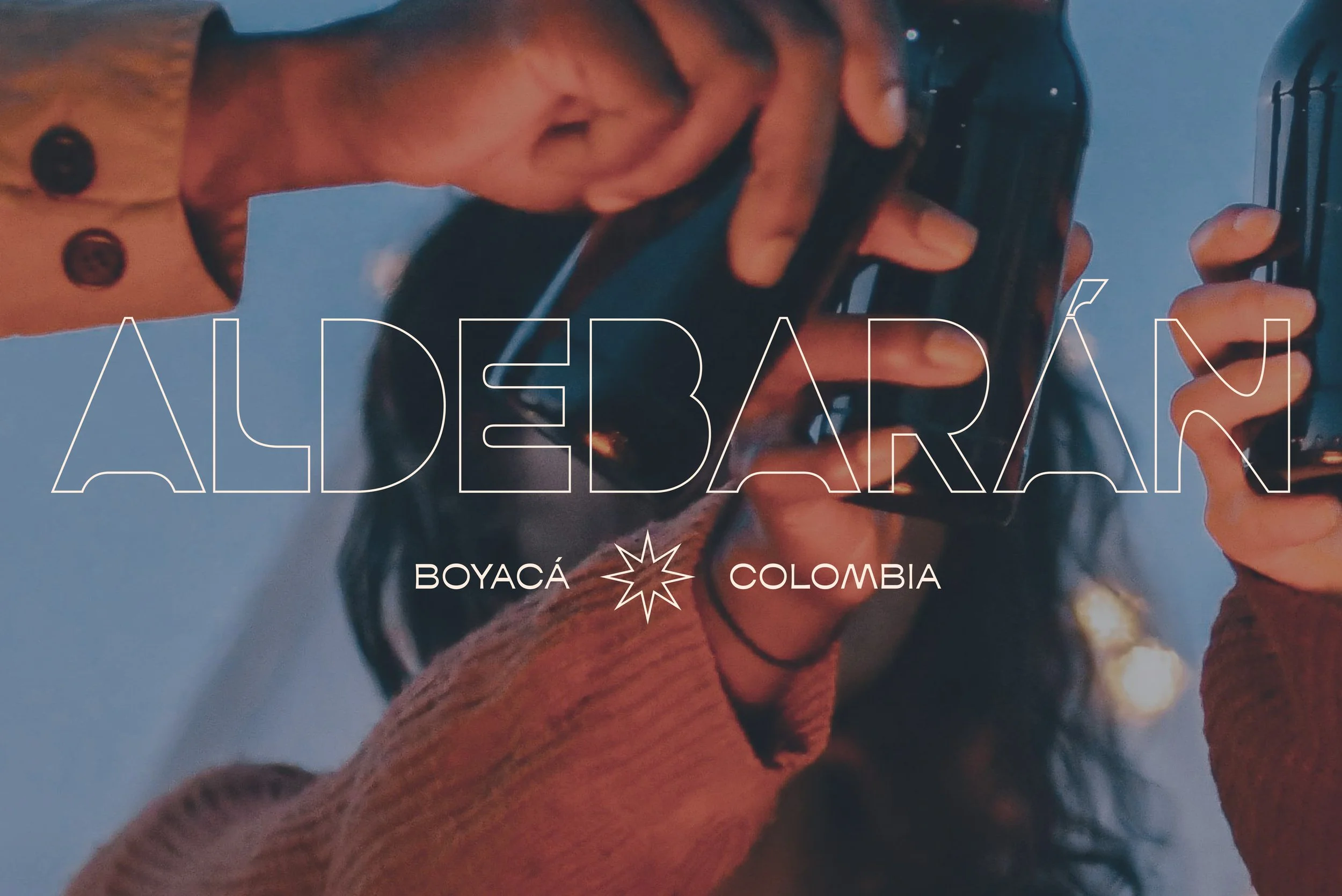 Two people holding dark glass bottles, possibly beer, with the text 'ALDEBARÁN' and 'BOYACÁ COLOMBIA' overlaid.