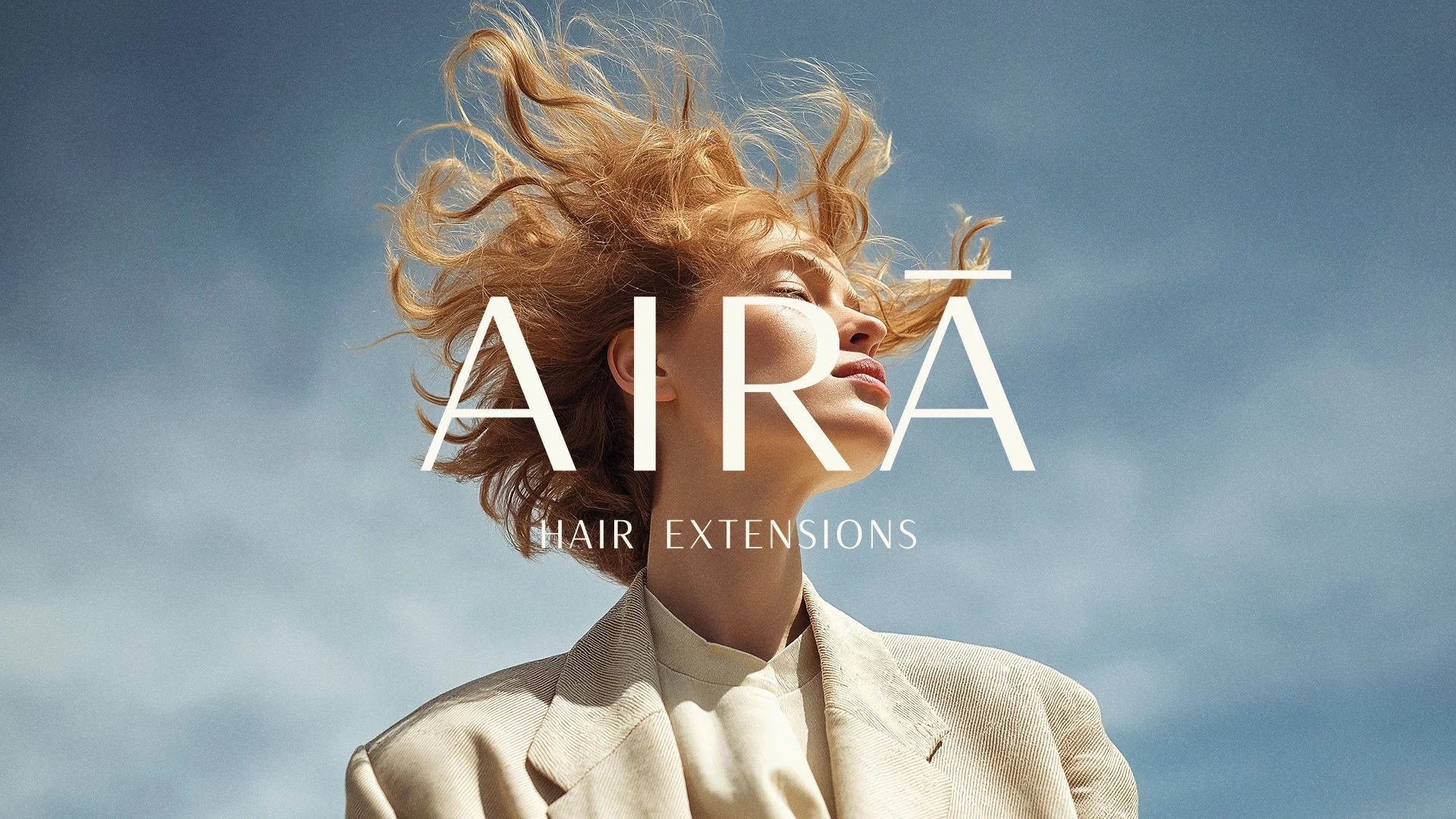 A woman with curly blonde hair outdoors against a blue sky, using hair extensions from Aura.