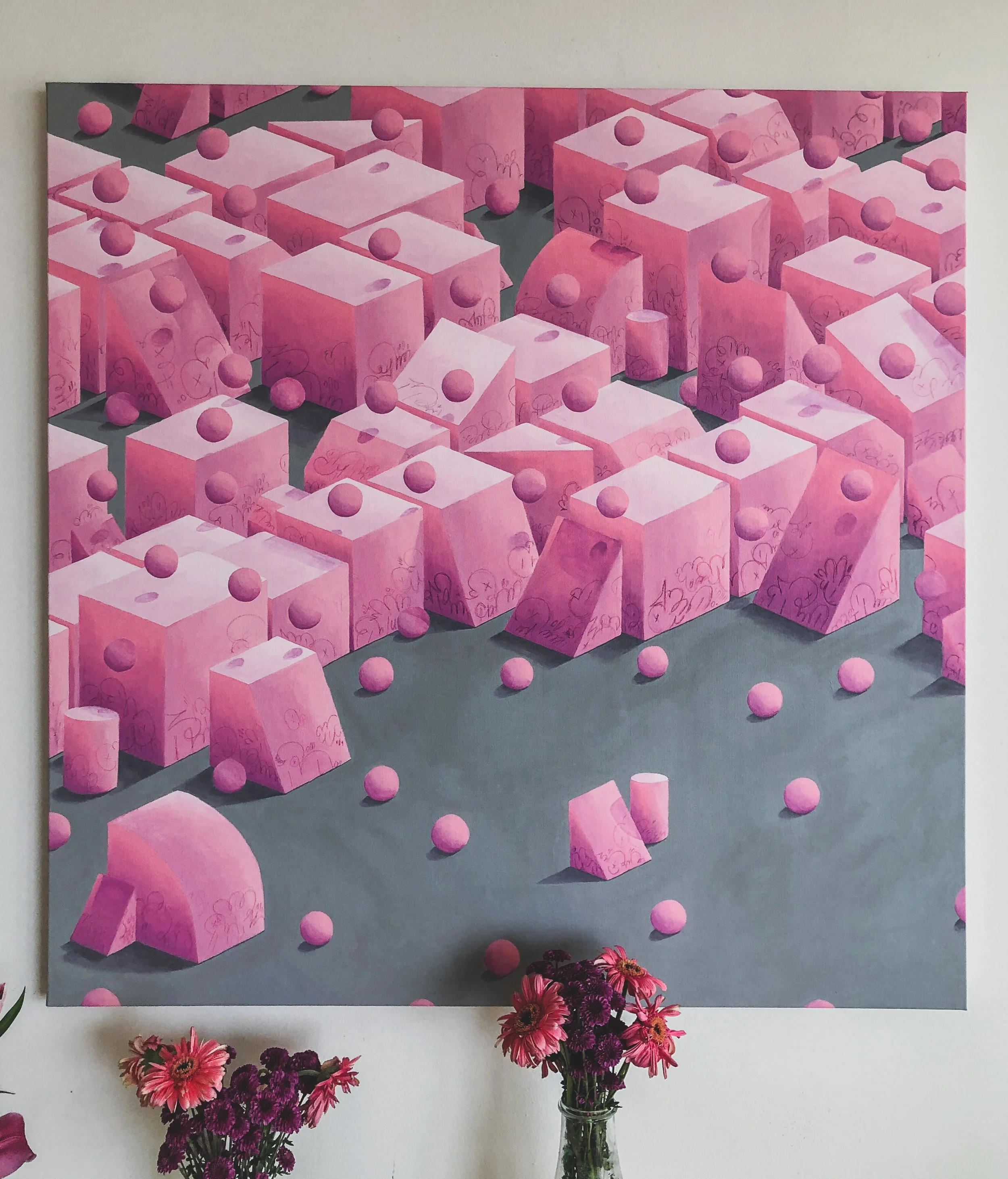 A painting featuring numerous pink geometric shapes, including cubes, cylinders, pyramids, and spheres, with some doodles on the shapes. There are pink flowers in vases at the bottom of the image.