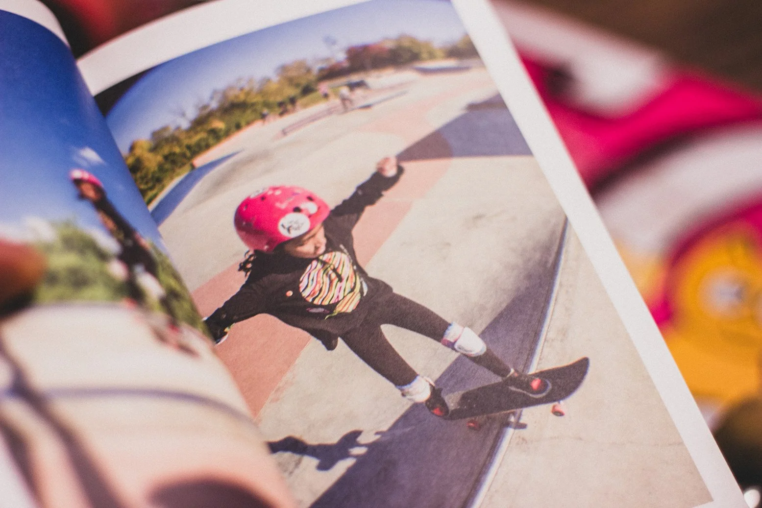 Child in a pink helmet skateboarding on a concrete skate park on a sunny day