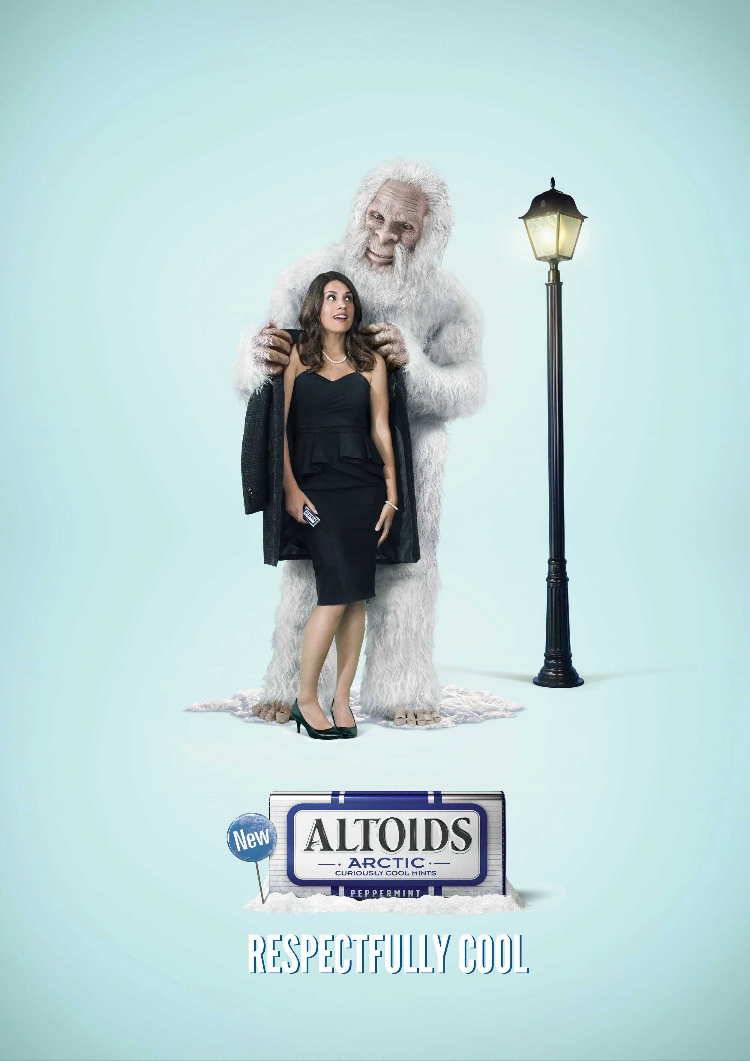 A woman in a black dress standing next to a person dressed as a large white yeti holding her shoulders with a friendly expression, at nighttime scene with a lamp post, promotional advertisement for Altoids Arctic mints, featuring the slogan 'Respectfully Cool'.