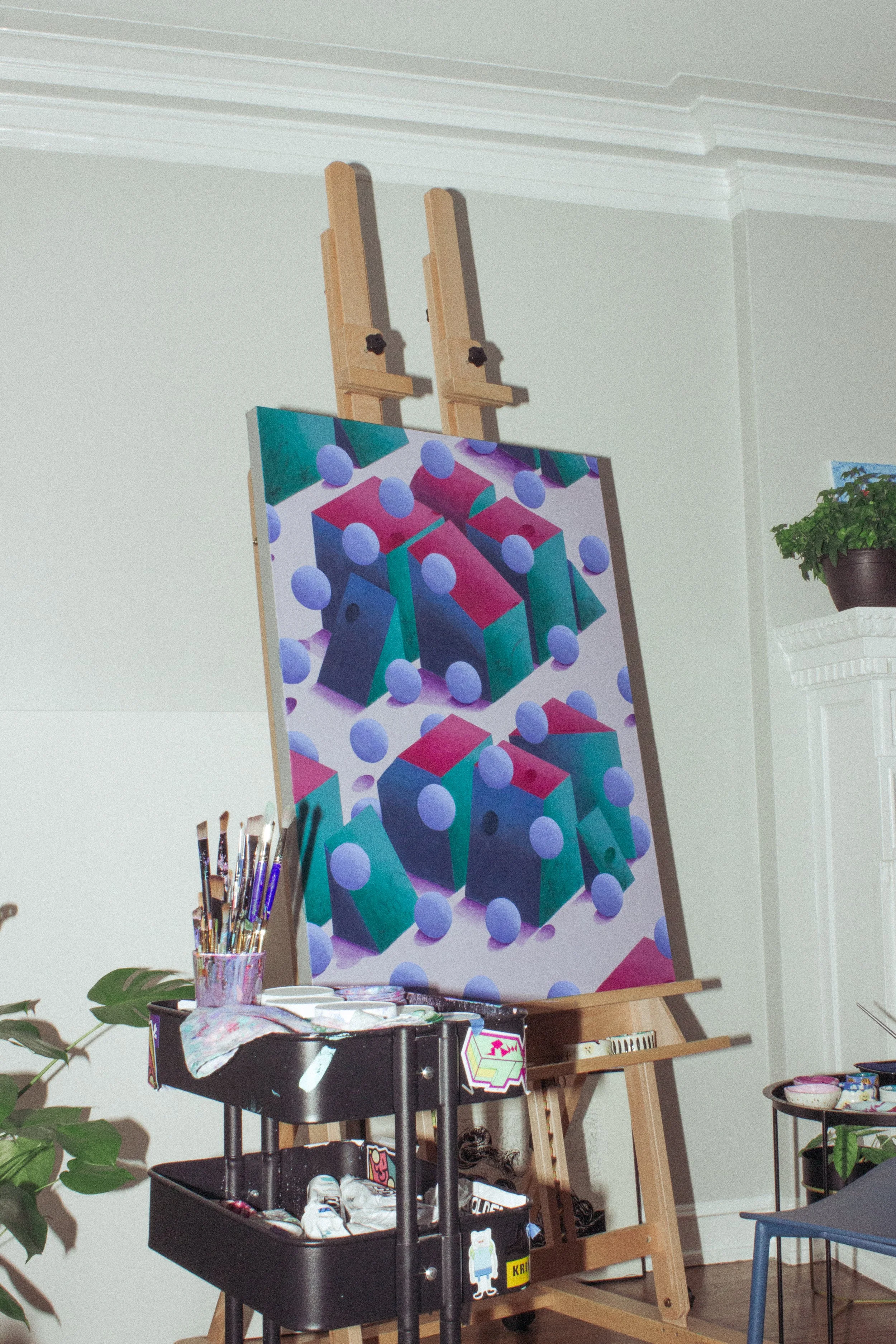 A painting on an easel depicting colorful geometric shapes and purple spheres.