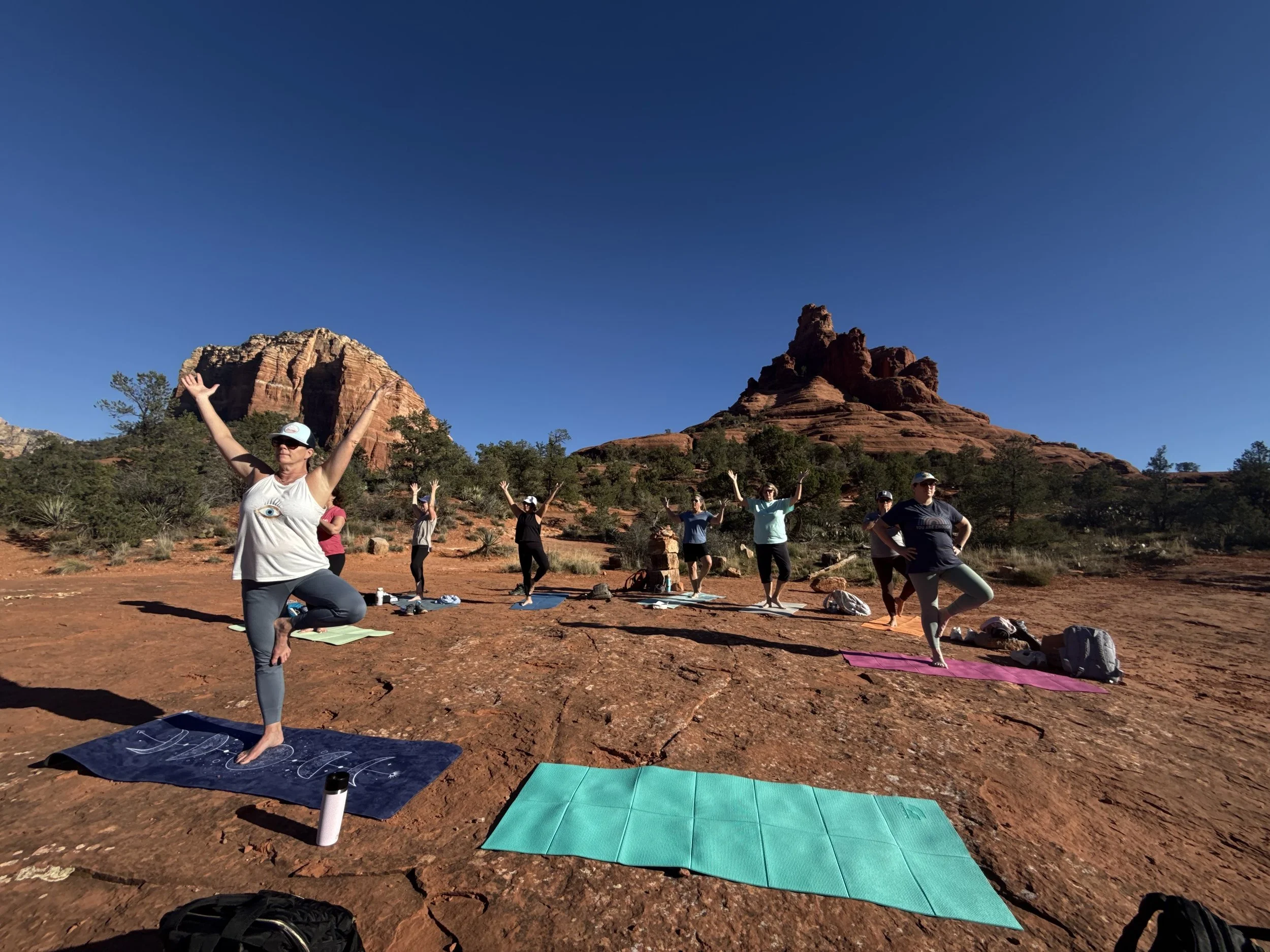 Attendees of the event in front of Sedona formations doing yoga.