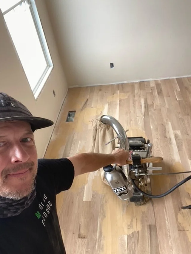 Hardwood floor refinishing using a professional belt sander in Cleveland, TN by MANdroid Flooring.