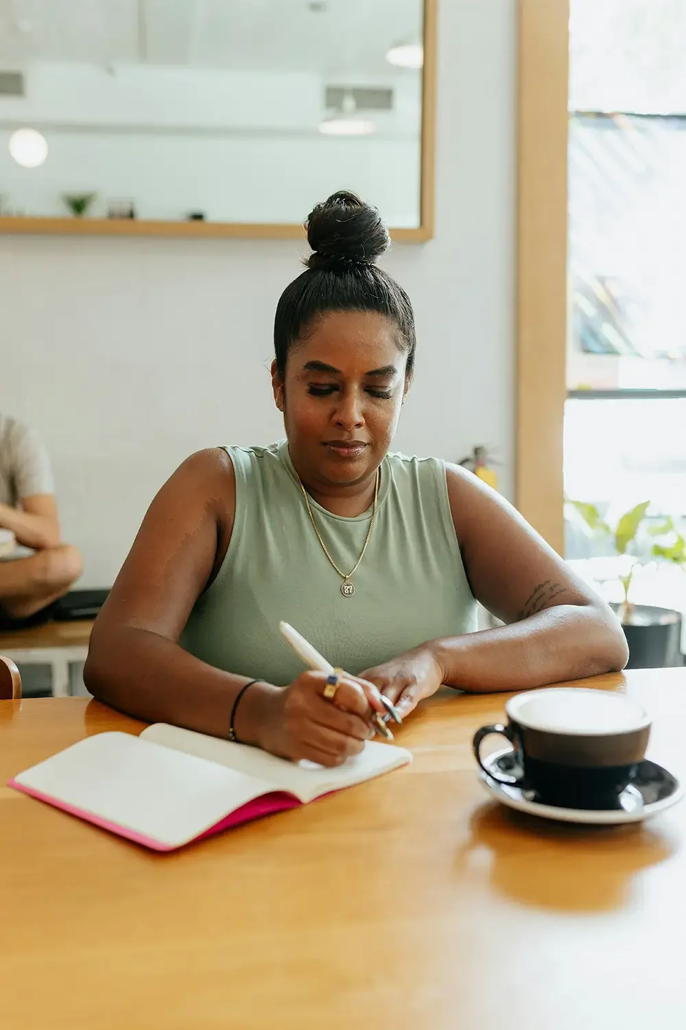 Woman with dark hair in a bun, writing with coach Cheryl Pallant.