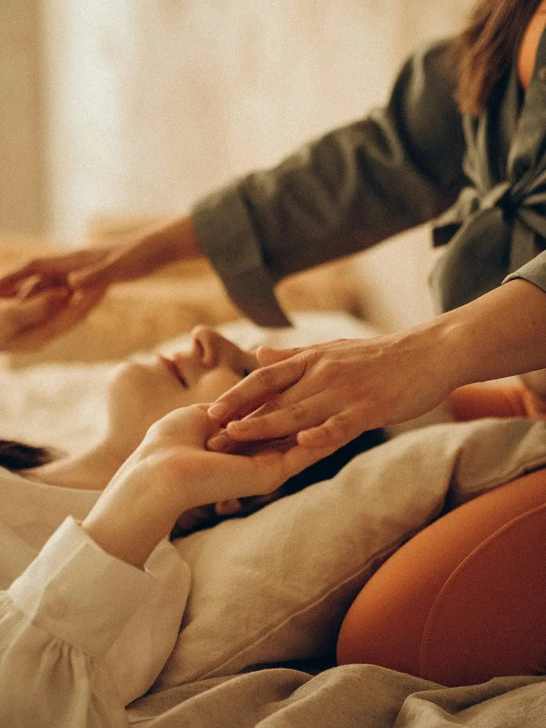 A person lying in bed with eyes closed, while Cheryl Pallant performs a Reiki session in Richmond, VA.