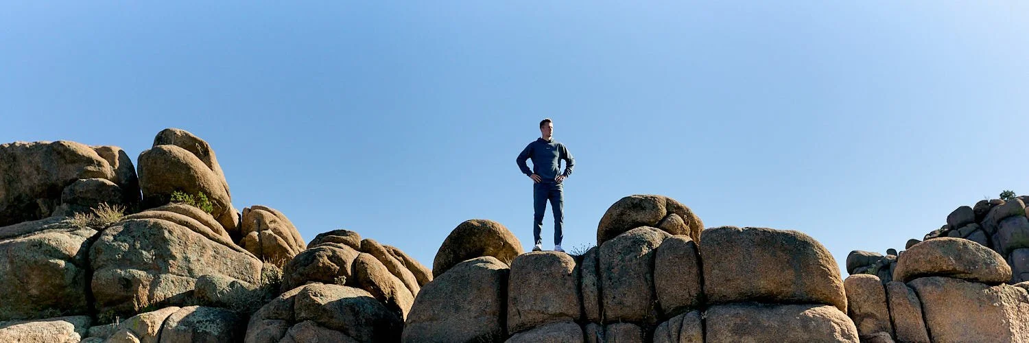Commercial lifestyle shot of athlete posing in sportswear on a mountain of rocks