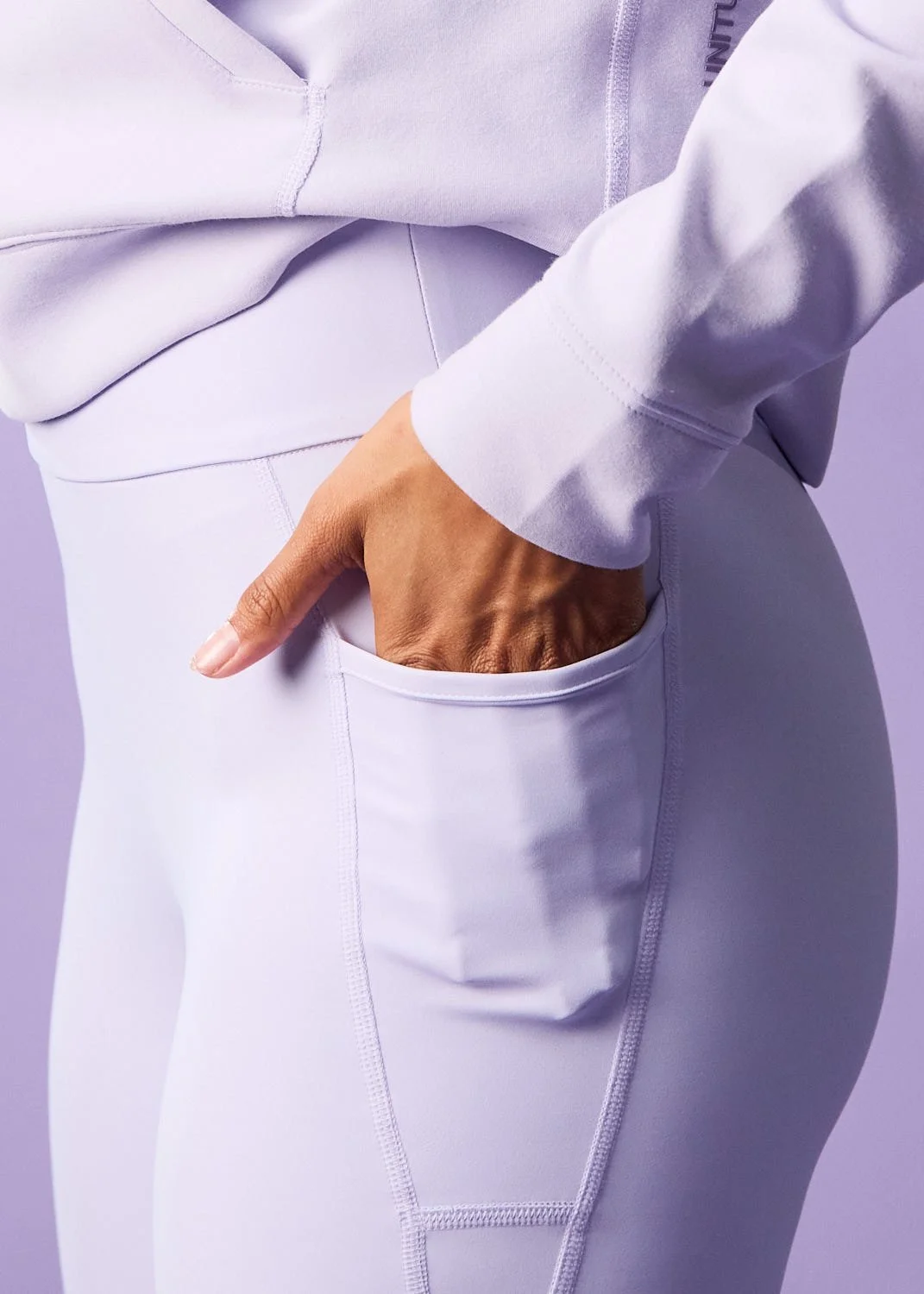 Women's purple outfit, model stretching, photographed with clean studio lighting