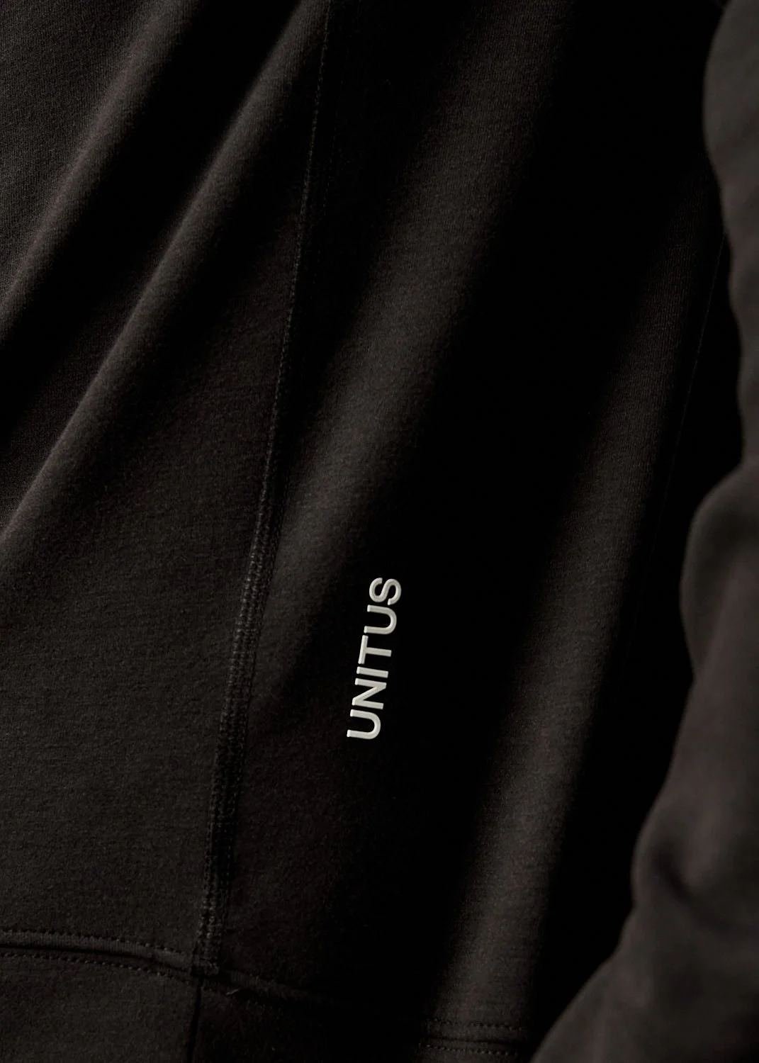 Detail of mens black athletic jacket with Unitus logo