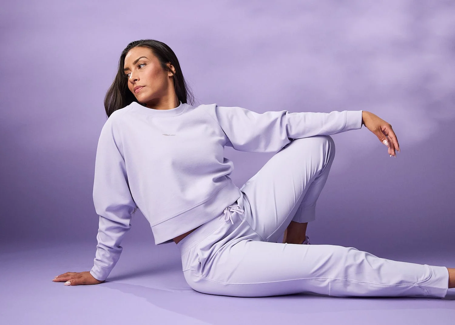 Women's purple outfit, model stretching, photographed with clean studio lighting