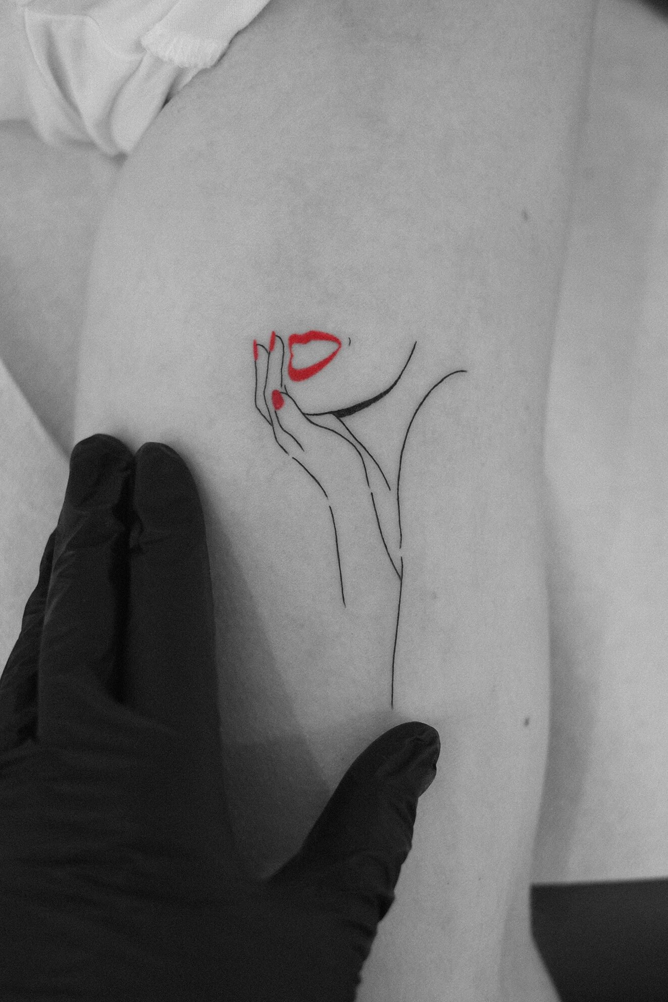 Dessin minimaliste représentant une femme avec des lèvres rouges et des ongles rouges, touchant son visage, tracé en ligne noire sur la peau nue.