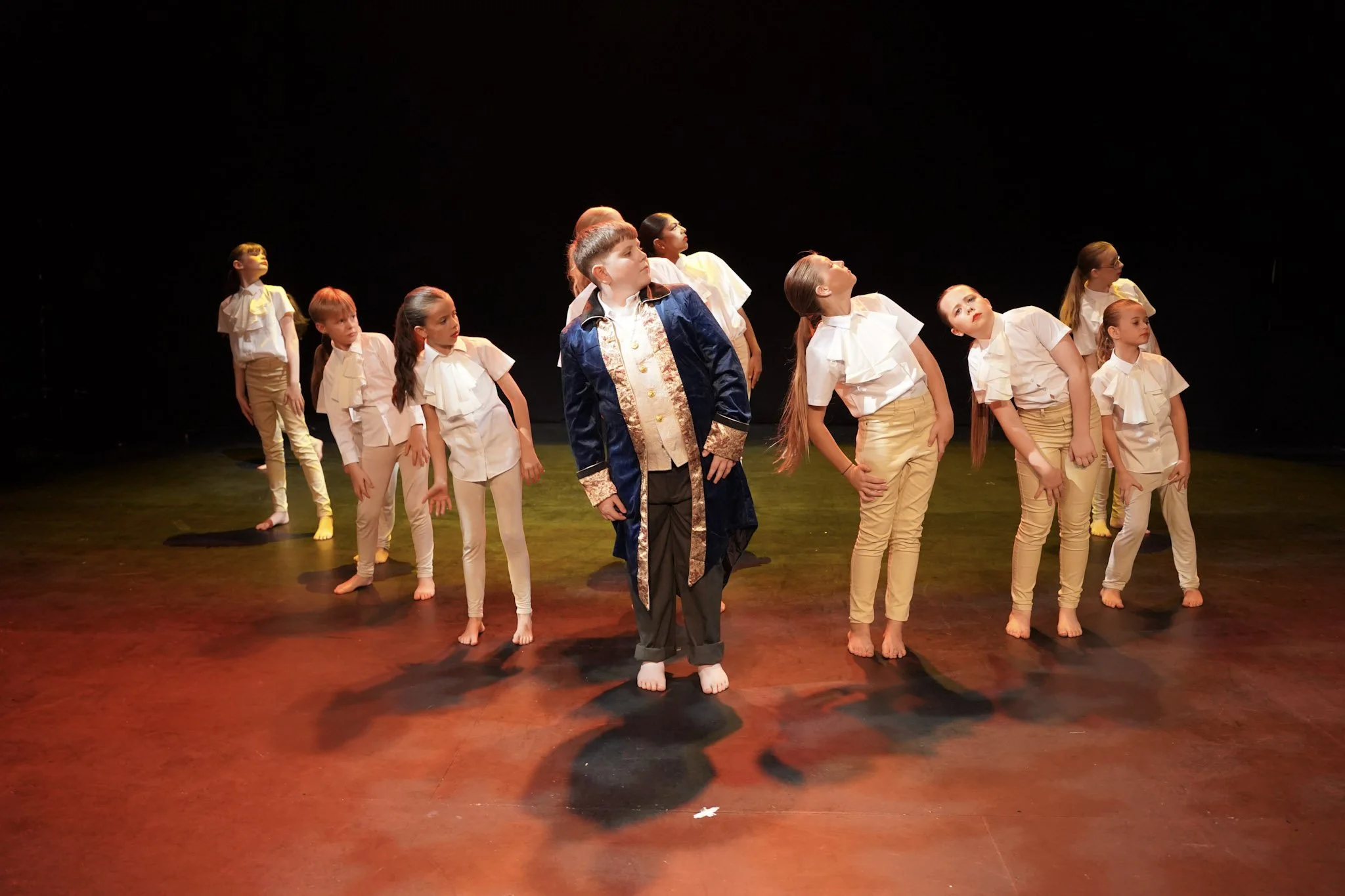 Children dressed in costumes performing a dance on stage.