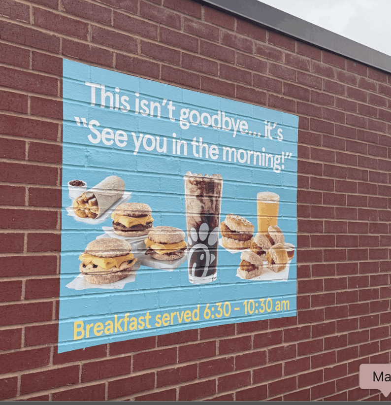 Chick-fil-A advertisement on a brick wall promoting breakfast items served from 6:30 to 10:30 am. The ad features images of breakfast sandwiches, hash browns, juice, and a soda, with a quote about saying goodbye and seeing you in the morning.