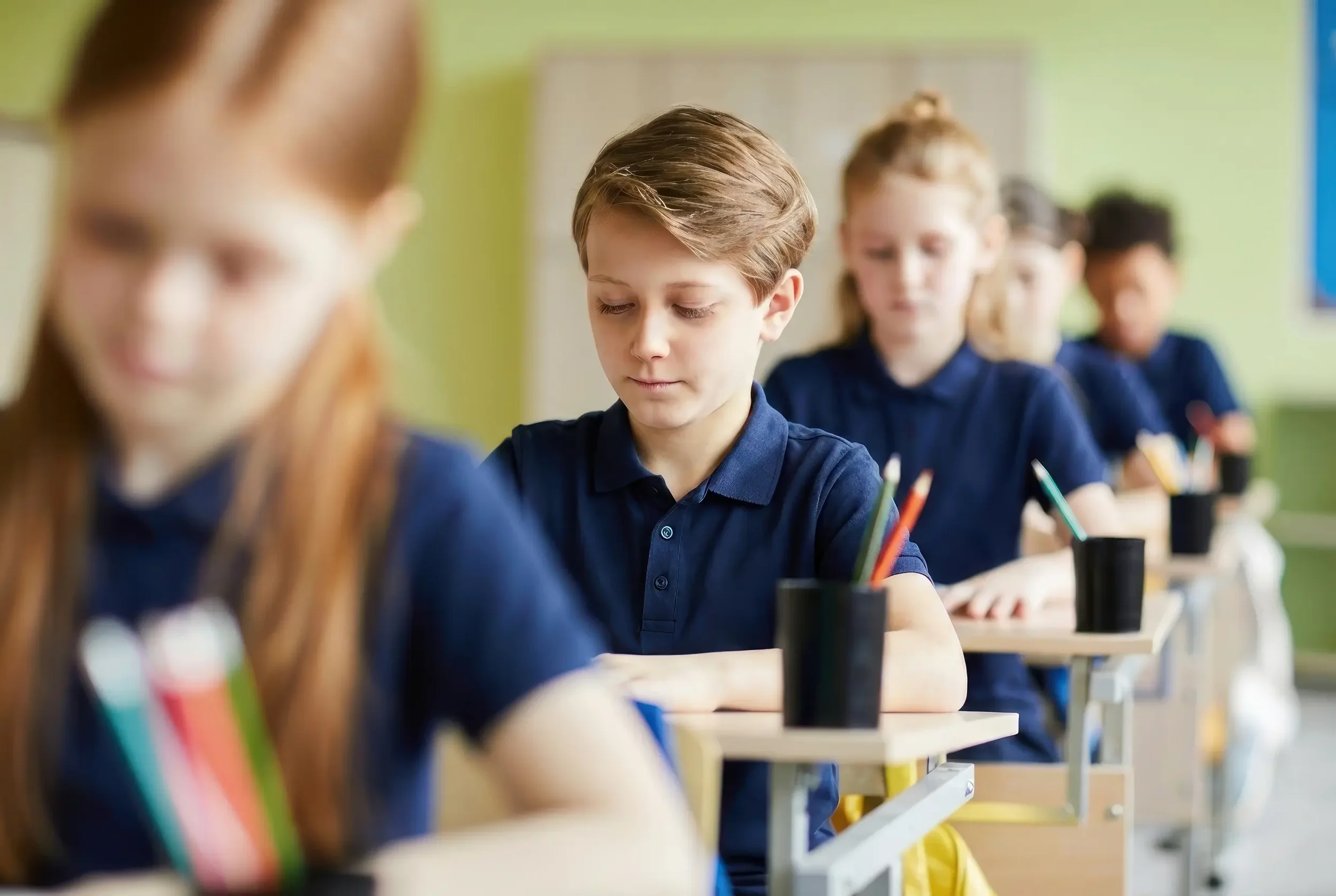 Students sitting in a row at their desks, focusing on their work in a classroom.