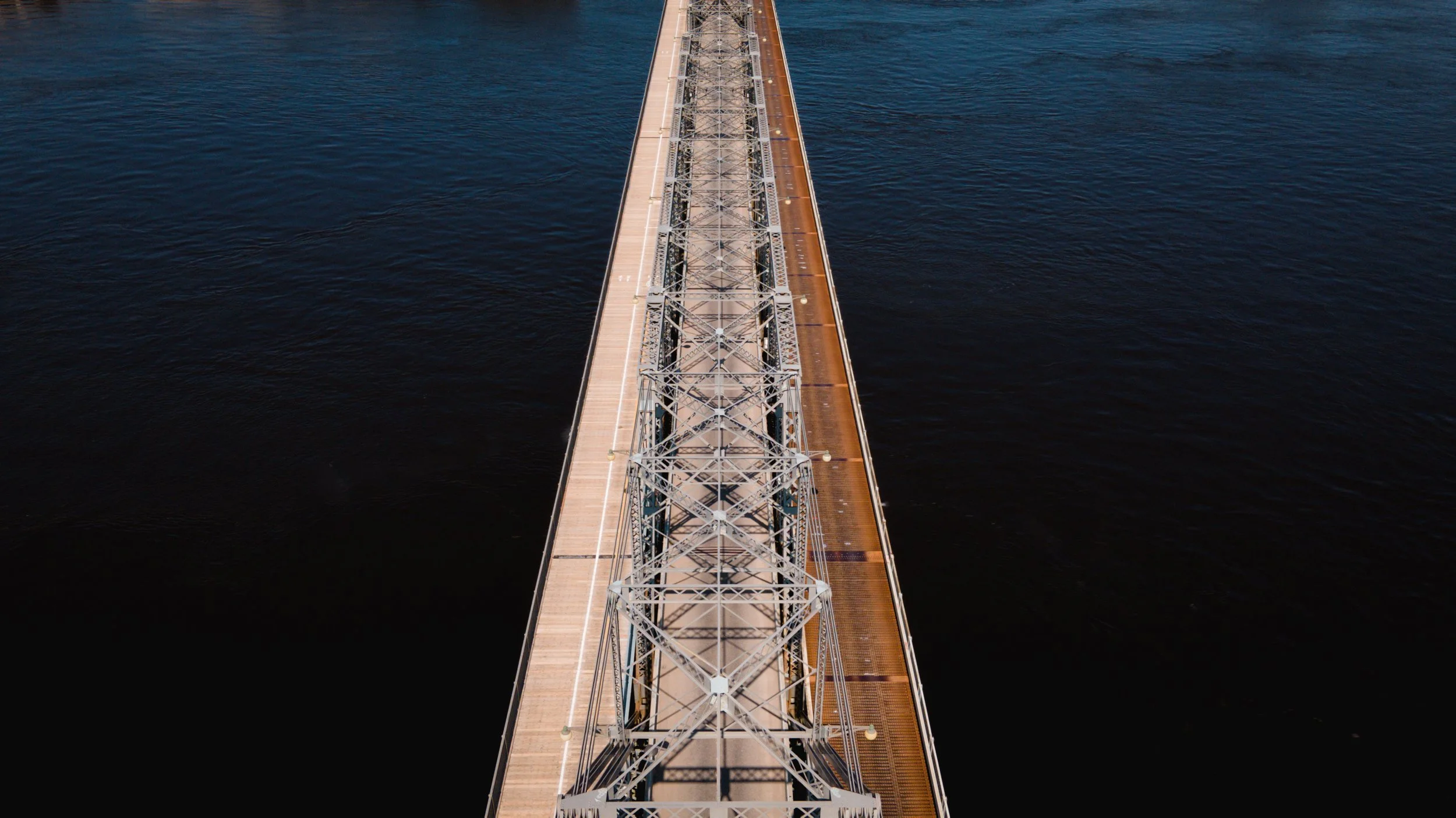  aerial view of a long bridge extending over dark water.
