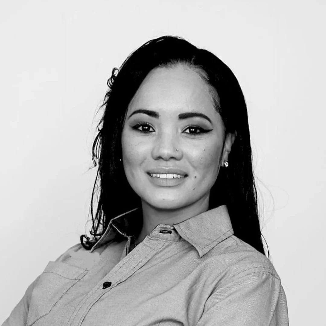 Black and white portrait of a woman with long dark hair, wearing a collared shirt, smiling at the camera.