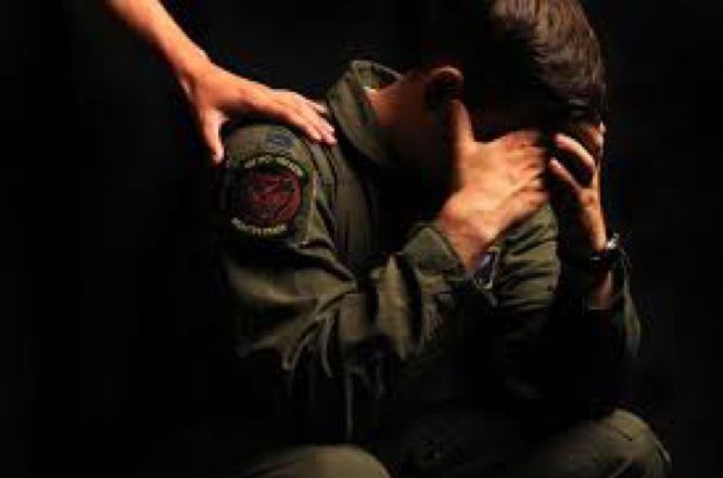 How To Diagnose PTSD and Treatment, person in military uniform is sitting with their head bowed and hands covering their face, while another person's hand is resting on their shoulder.