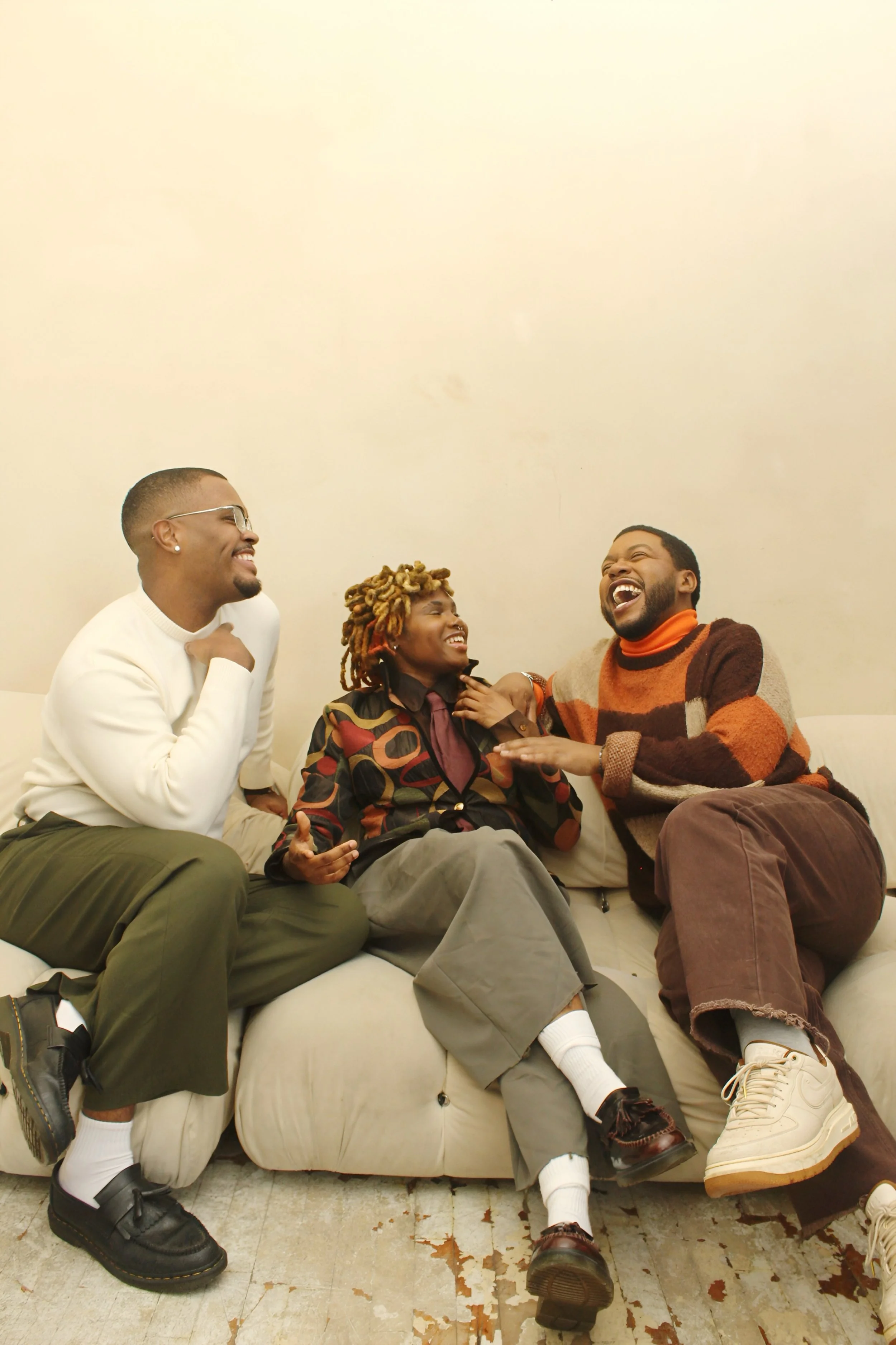 Three friends sitting on a couch, laughing and enjoying each other's company.