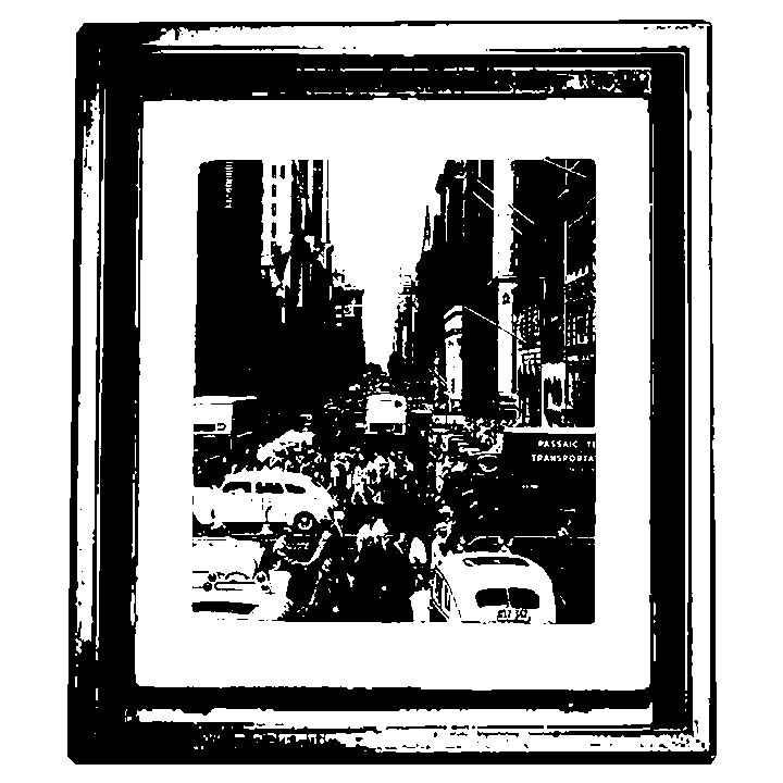 Black and white photograph of a busy city street with tall buildings, cars, and pedestrians, viewed from across the street.