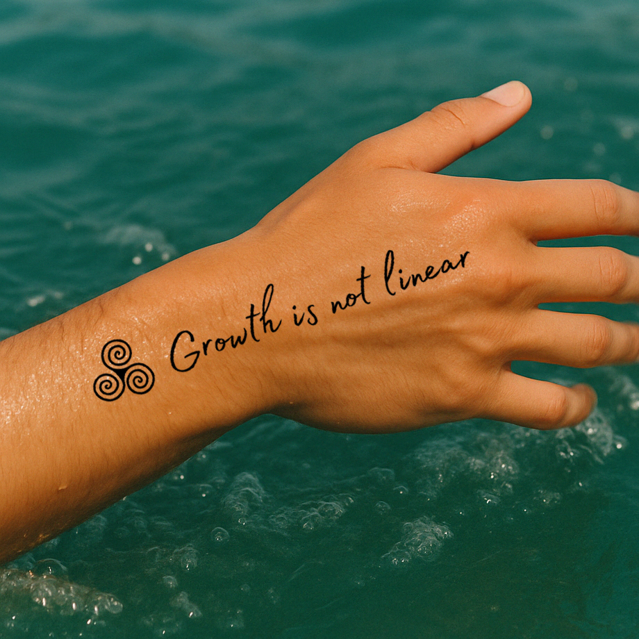 A hand over the water shows a tattoo in cursive that says "growth is not linear" and it has the symbol of the triskelion also known as the triple spiral symbol. 