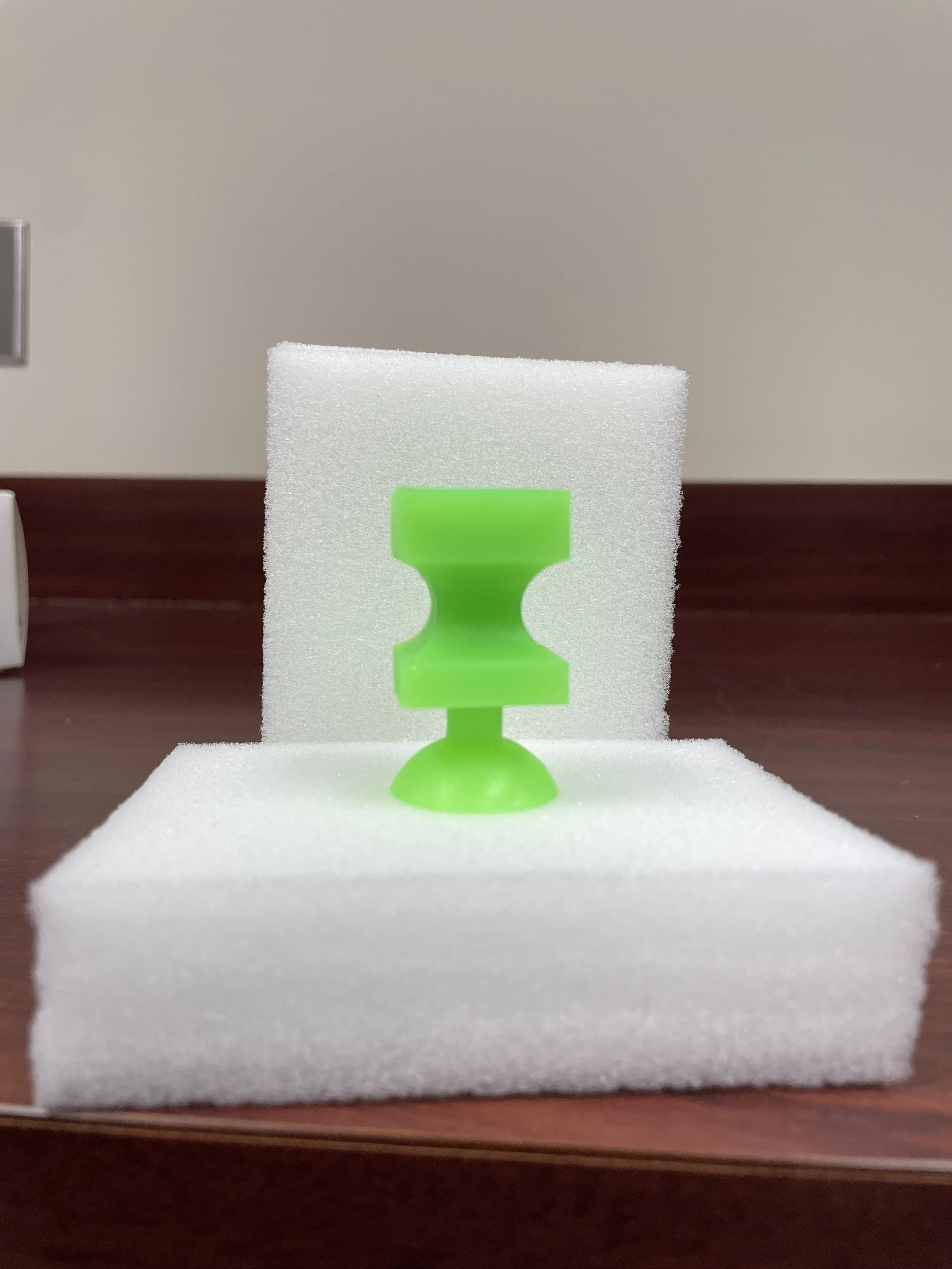 The Product being a bright green silicone card picker upper on a piece of white foam.
