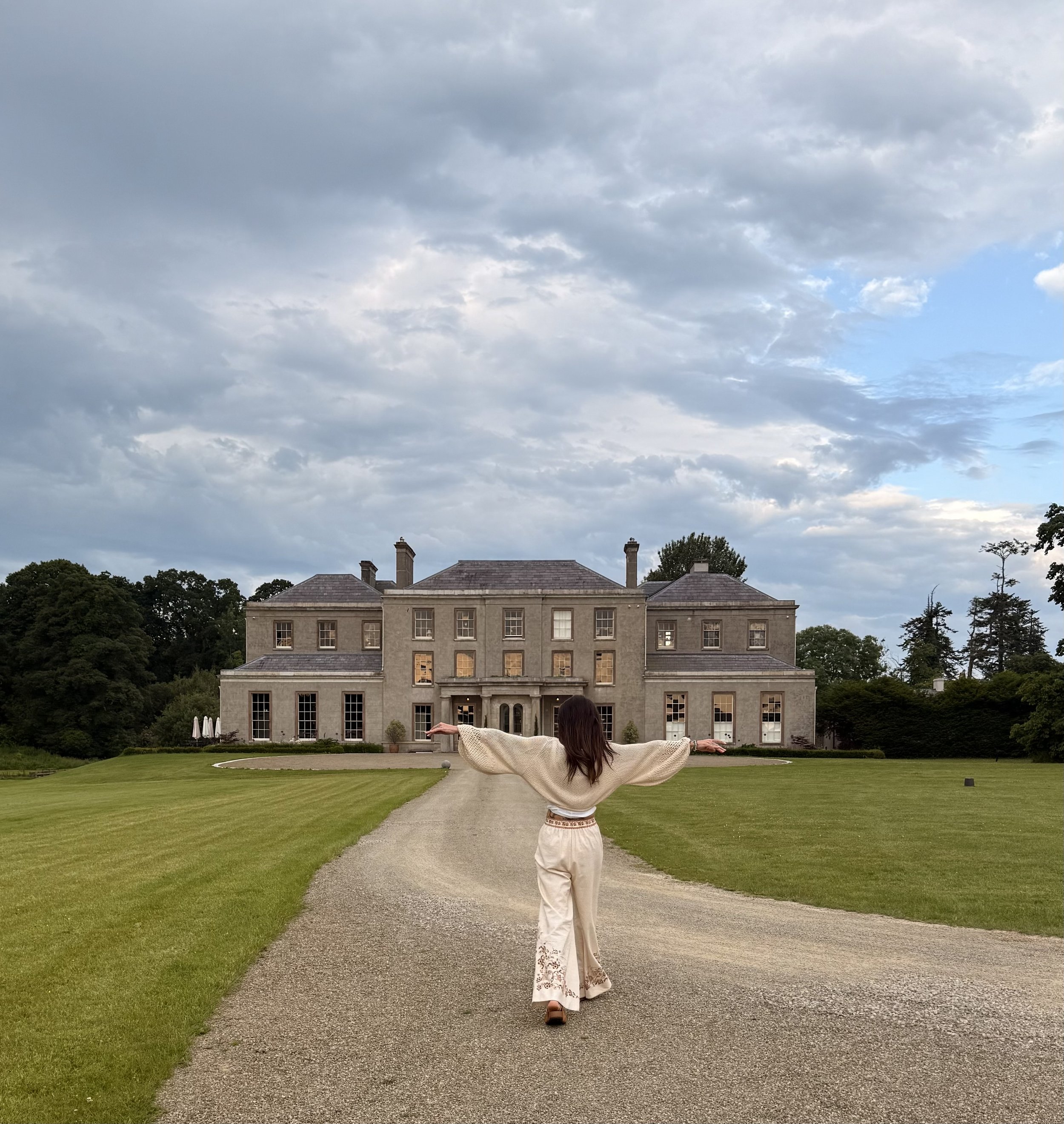 Pixi in front of a large manor house