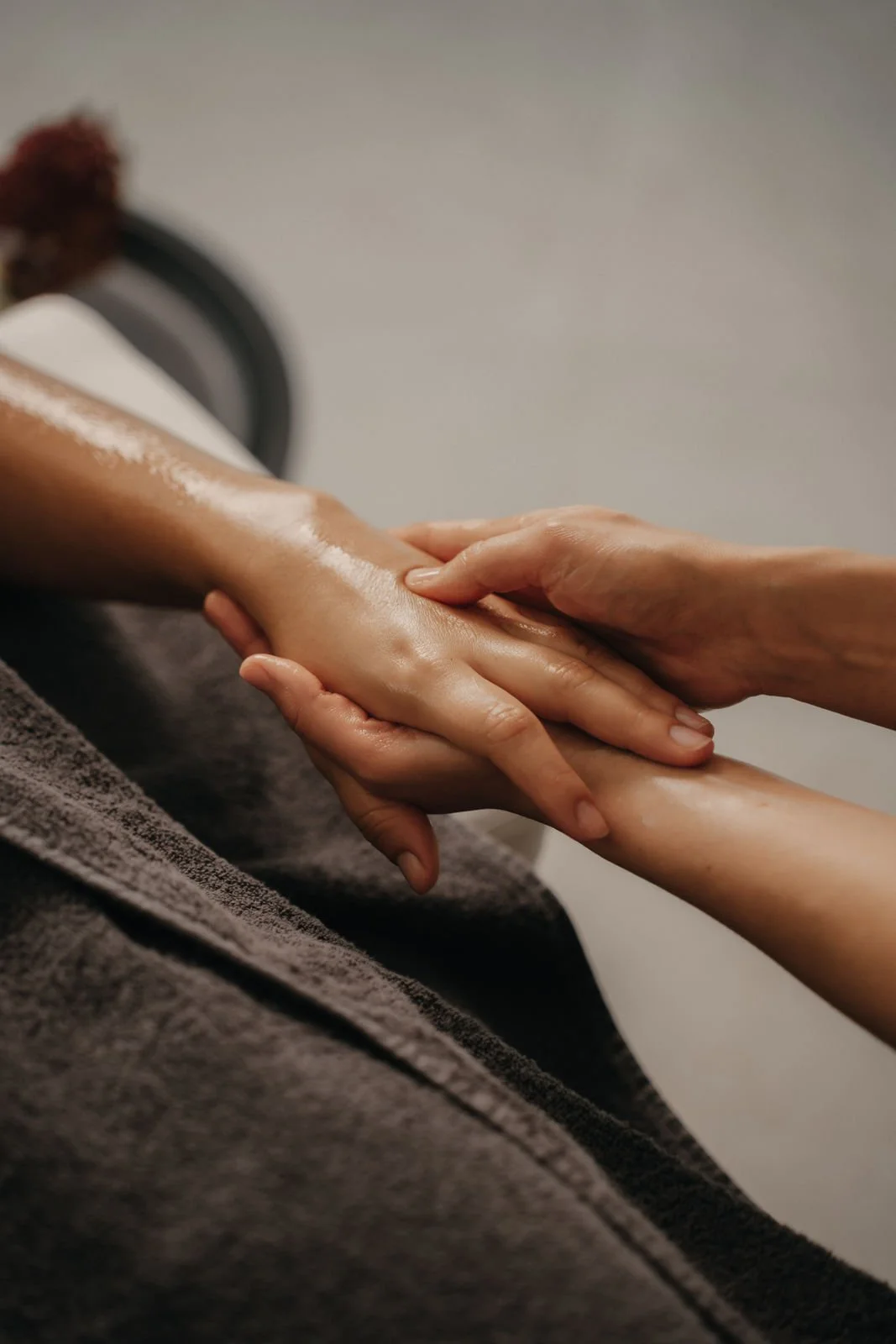 Gros plan sur un abdomen féminin nu, avec une main posée sur le haut de l'abdomen et une autre main sur la hanche, portant un bracelet noir. La personne porte un haut gris et un sous-vêtement noir.