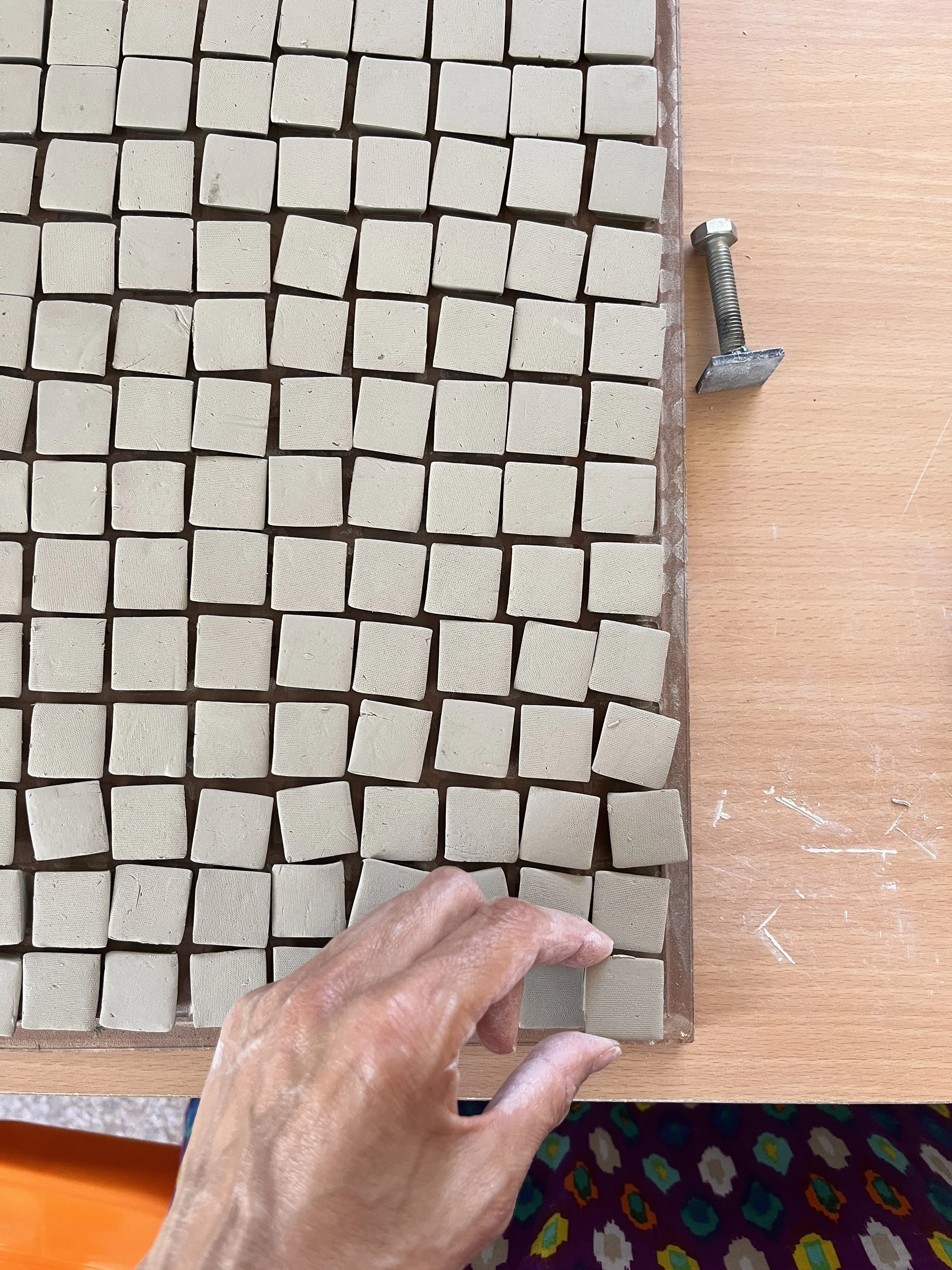 Pièces de porcelaine non cuites, découpées avec une spatule selon un emporte-pièce de 2cm carré. Etape réalisée avec Amin Bakhti, céramiste marocain, Maroc juin 2024.