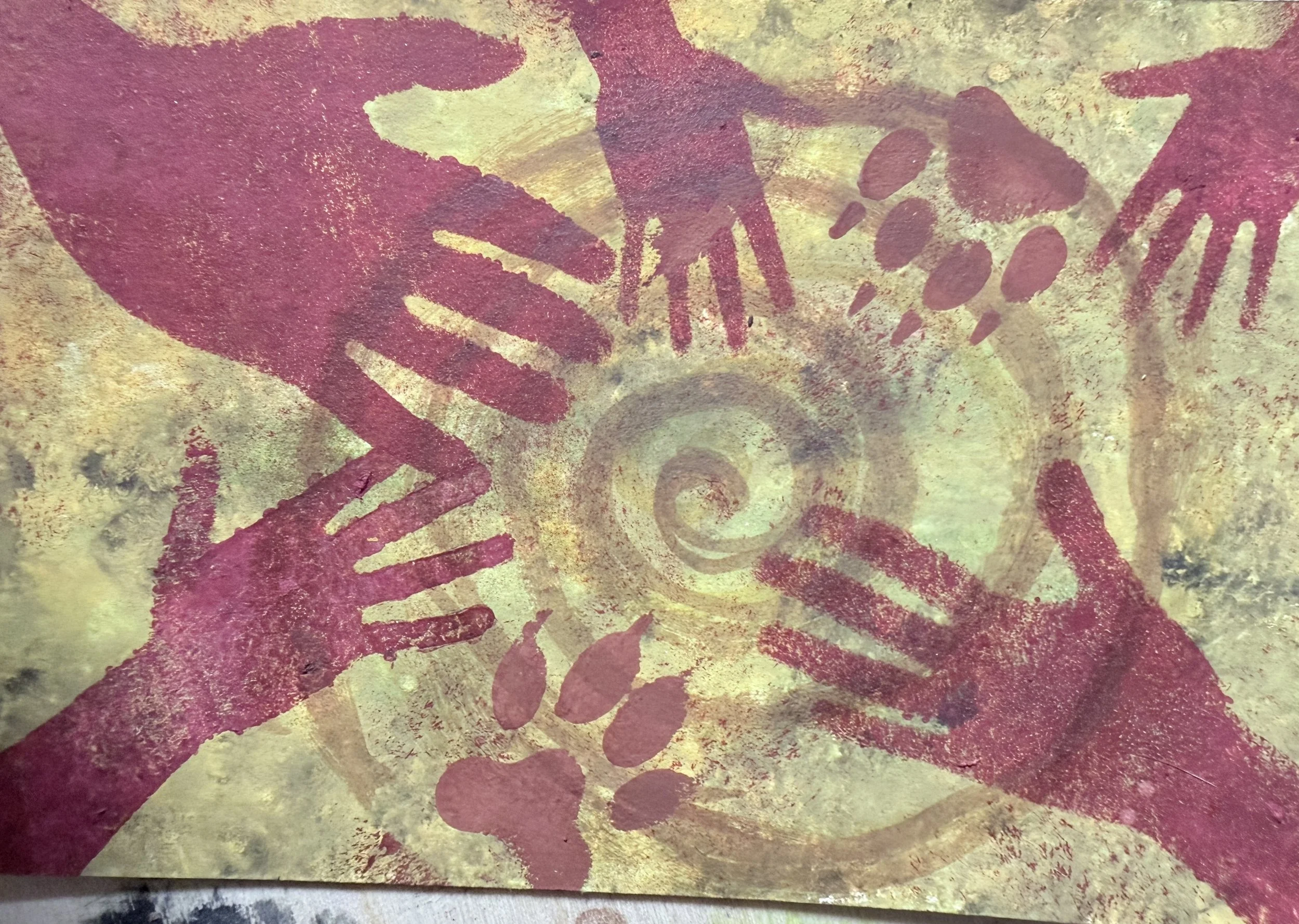 Watercolor of red handprints over ochre with paw prints and a soft spiral