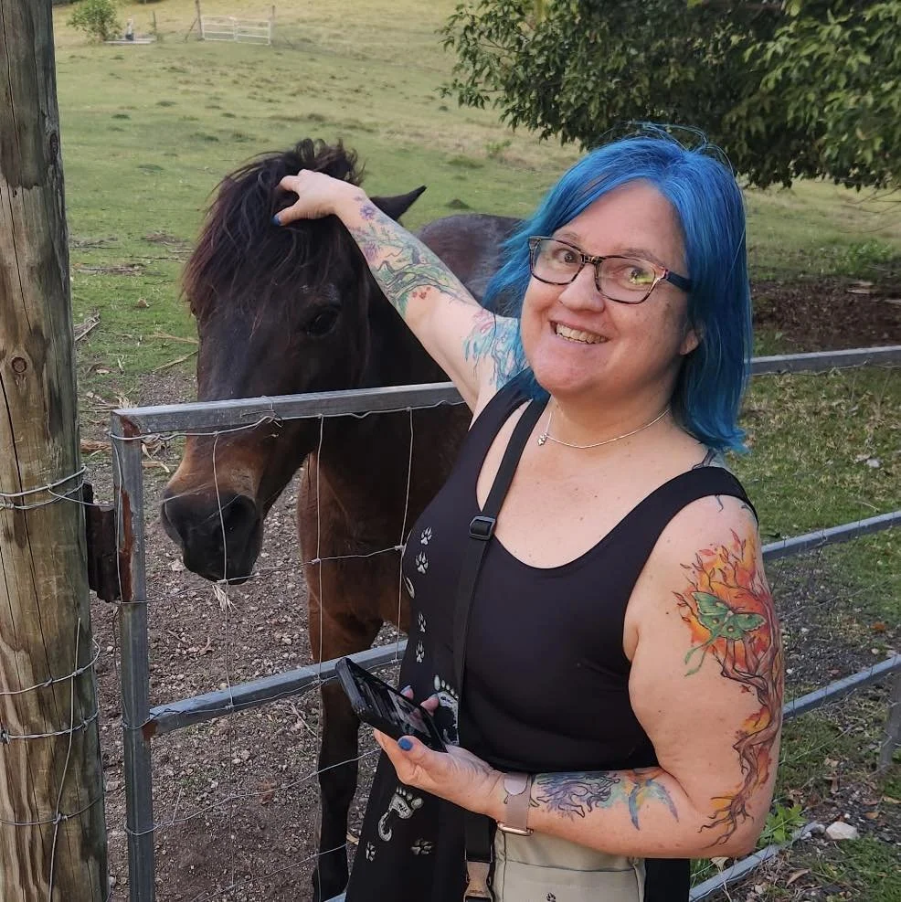 Woman with blue hair petting a horse