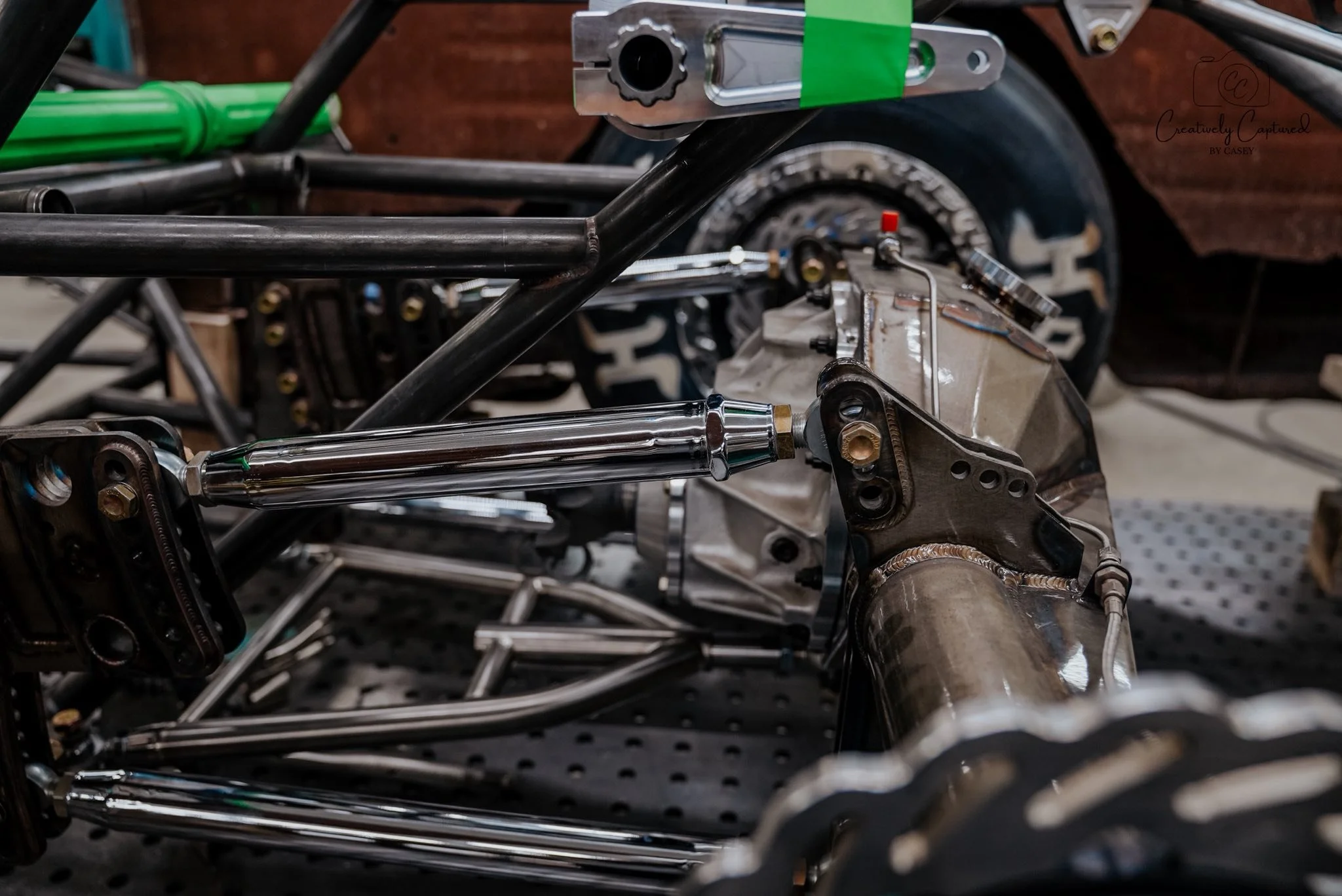 Close-up of a metal chassis and suspension components of a race car under construction.