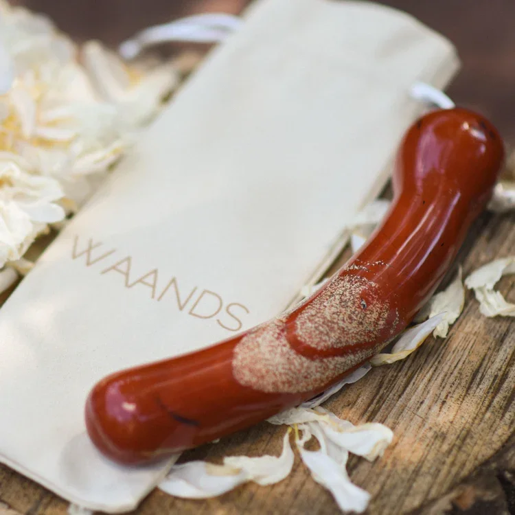 A wax seal stamp with red wax on a piece of paper that says 'W A N D S' surrounded by white flower petals. Crystal Wands for pleasure