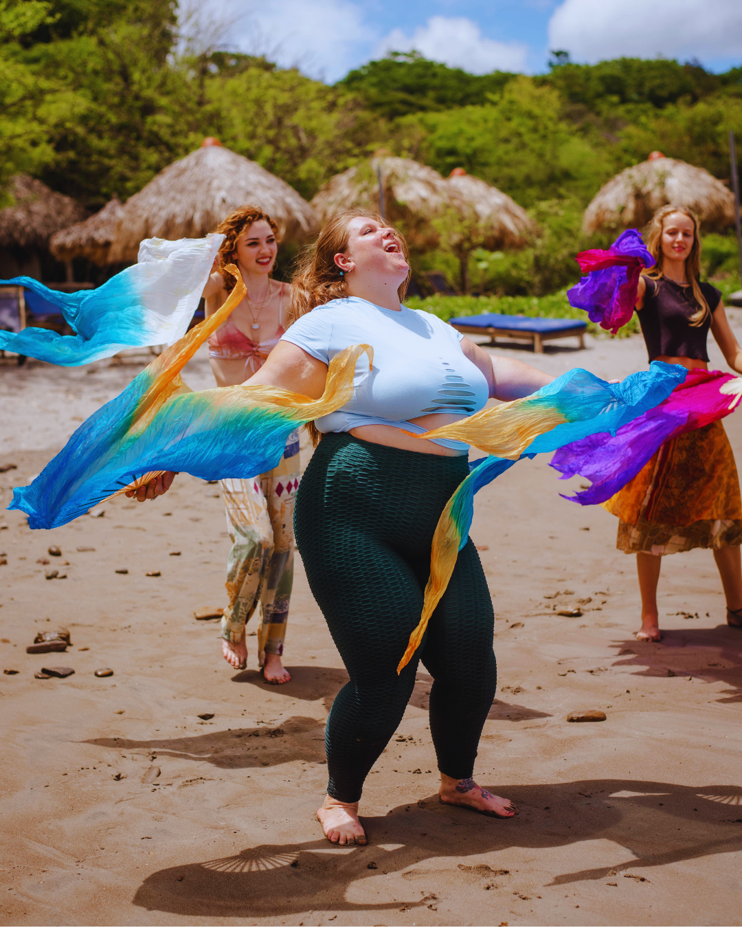 A woman playing with silk fans, flowing,  happy to share a review for Honeybee Love Alchemy's Sensual Radiance Program