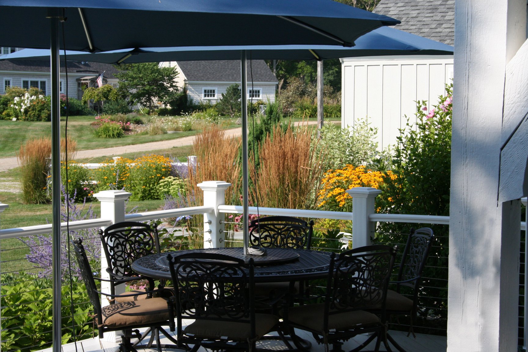 Seabreeze Cottage features a charming white picket fence, lush coastal plantings, and a welcoming New England landscape designed to enhance curb appeal and outdoor living. This timeless residential landscape by Sea Laurel Landscape Architecture blend