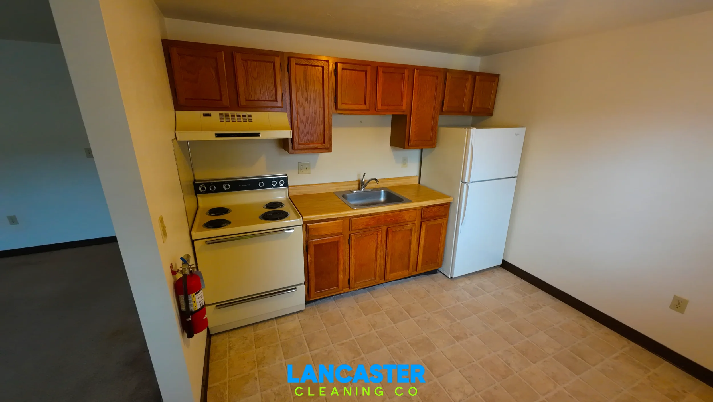 Lancaster, PA apartment kitchen after a move-out cleaning service, showing a fully cleaned rental unit with sanitized cabinets, countertops, stove, sink, refrigerator, and spotless vinyl flooring.