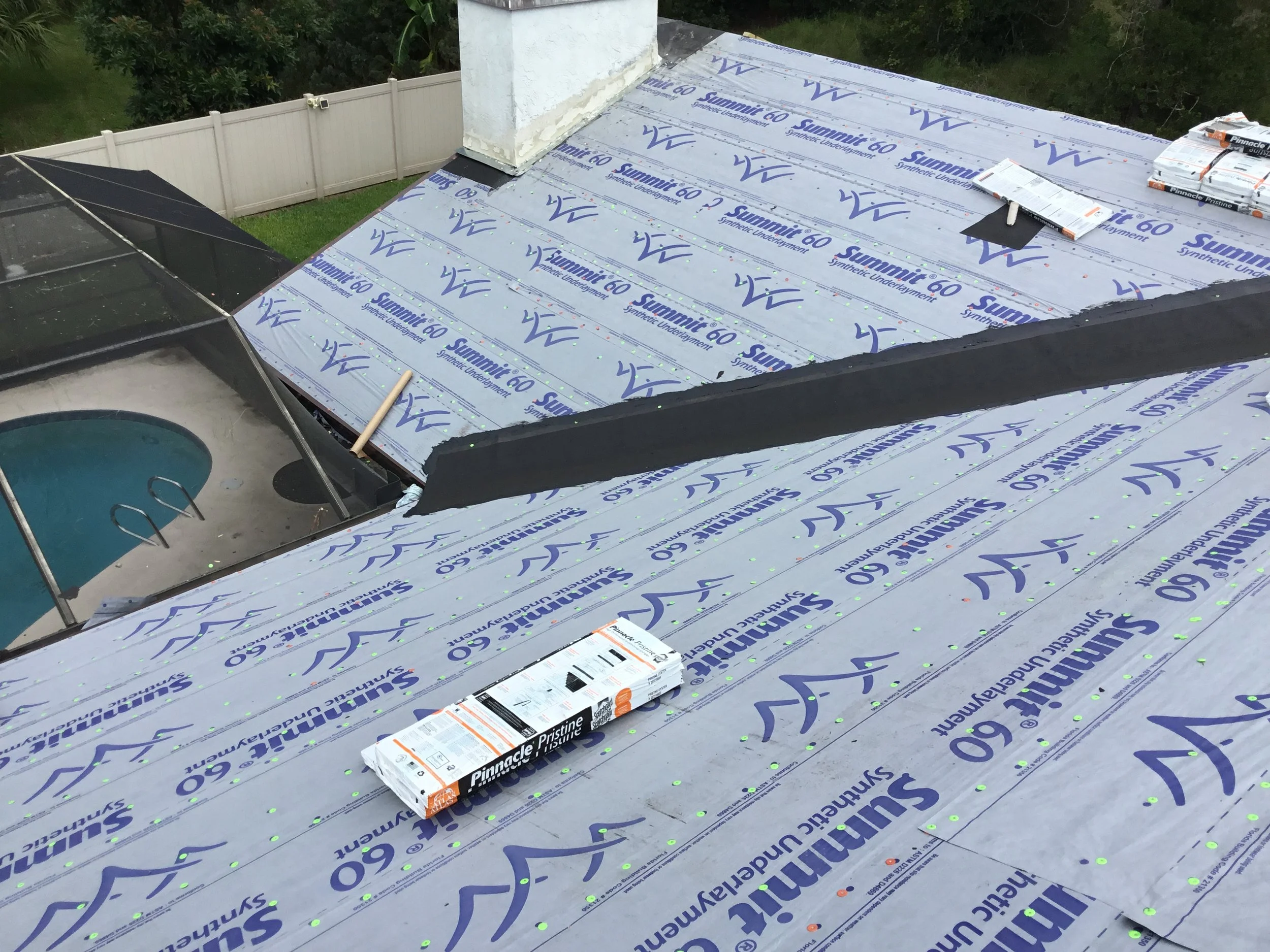 High-performance synthetic underlayment installed across the roof deck with peel-and-stick membrane correctly applied in the valley as required by code, along with properly integrated chimney flashing. This layered approach creates a robust waterproo
