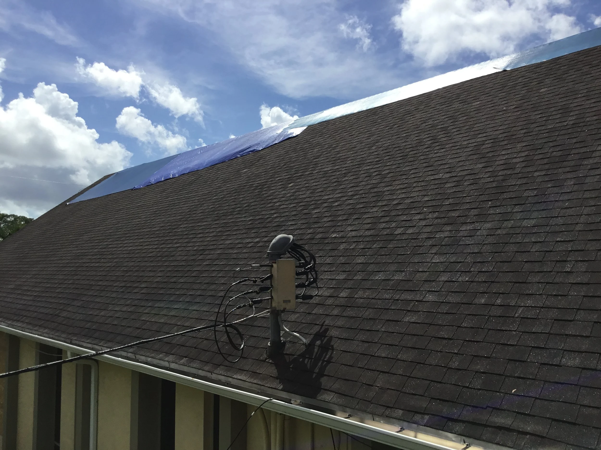 Close view of the original DeLand church asphalt shingle roof prior to replacement, showing surface wear, granule loss, and weathering along the ridge. This level of aging reduces wind resistance and water-shedding ability, illustrating why a full re