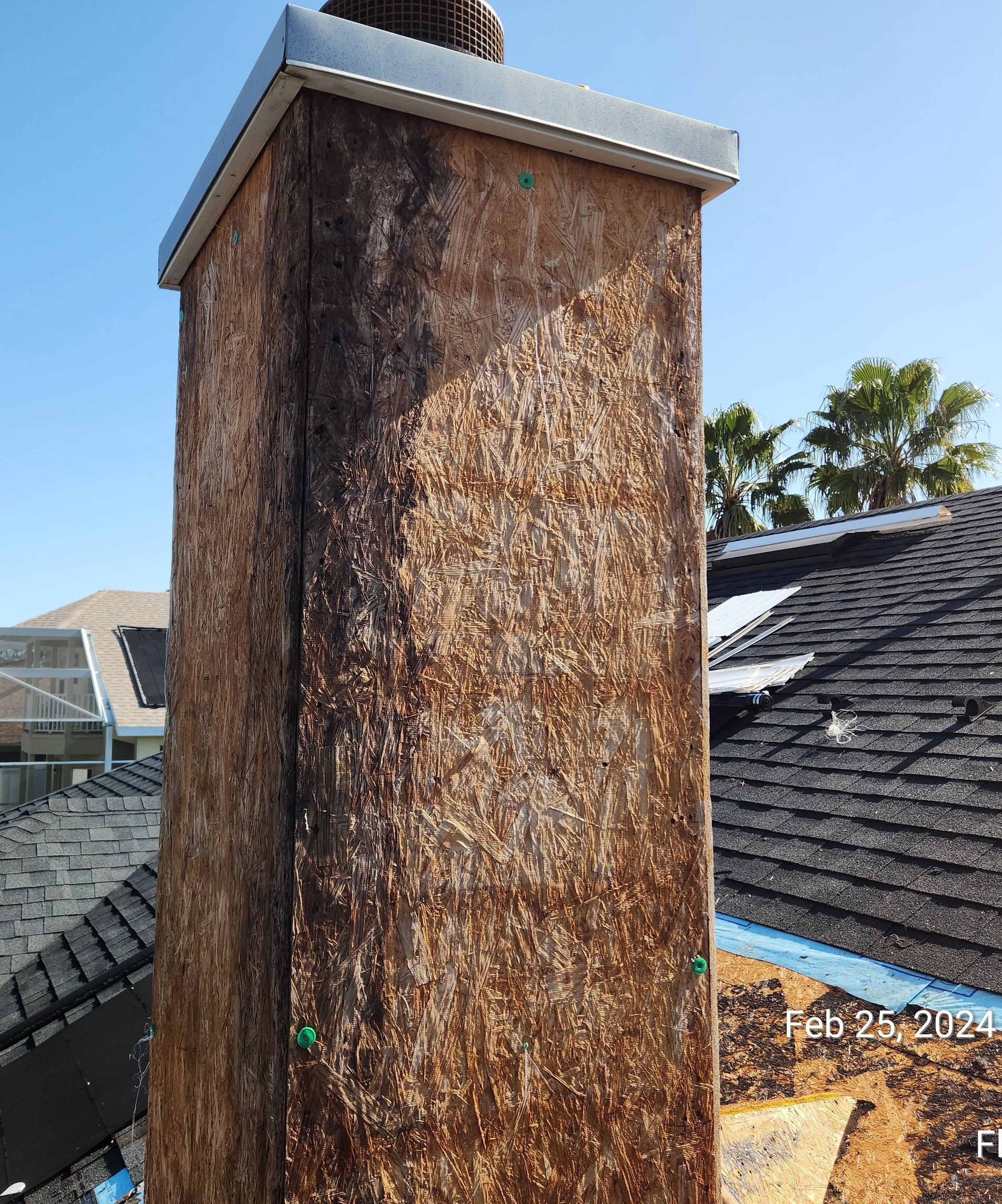 Chimney showing severe wood rot caused by long-term water intrusion, where deteriorated framing and sheathing indicate chronic flashing failure. Once moisture is trapped behind the chimney chase, decay spreads quickly into structural members — which 