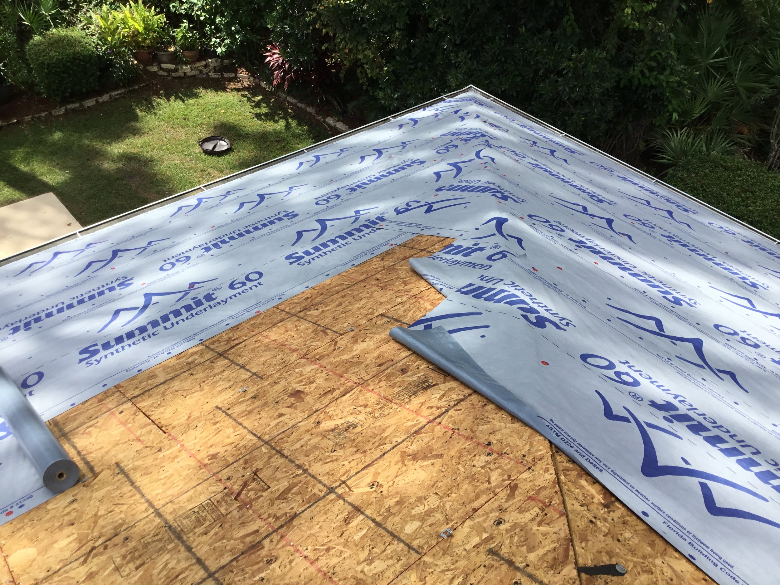 High-performance synthetic underlayment being installed over roof decking before final roofing materials are laid. This advanced layer provides a tough secondary water barrier, improves walkability during construction, and protects the home from wind