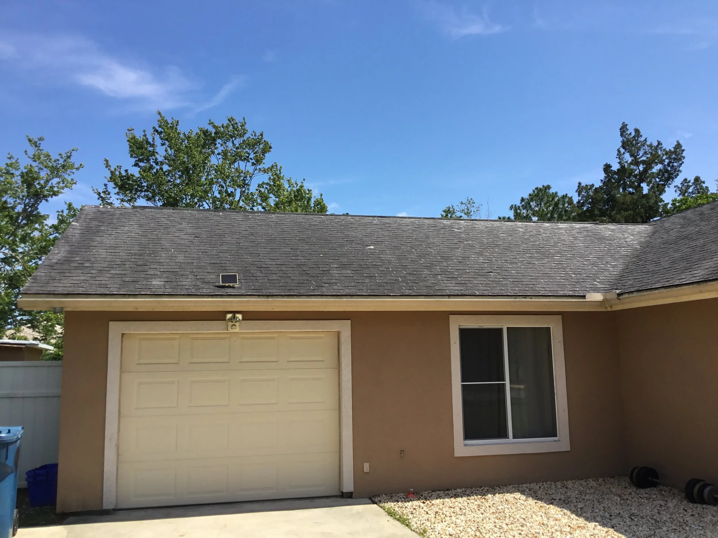 Aging asphalt shingle roof where exposed fiberglass matting is visibly “shining” through worn granules — a clear sign of advanced deterioration. Once granule loss reaches this stage, shingles no longer properly protect the roof from UV damage or wate