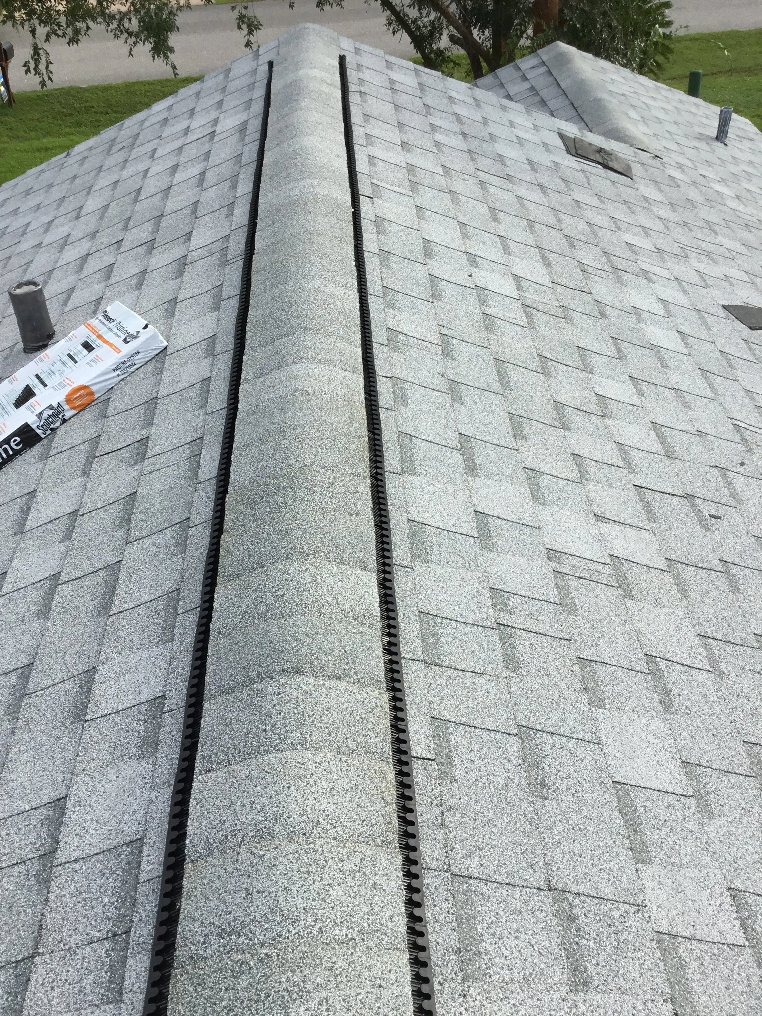 Final finishing work on a gray architectural shingle roof replacement, showing clean ridge detailing, properly seated caps, and tight edge alignment. These last steps ensure weather protection, consistent appearance, and long-term performance — the d