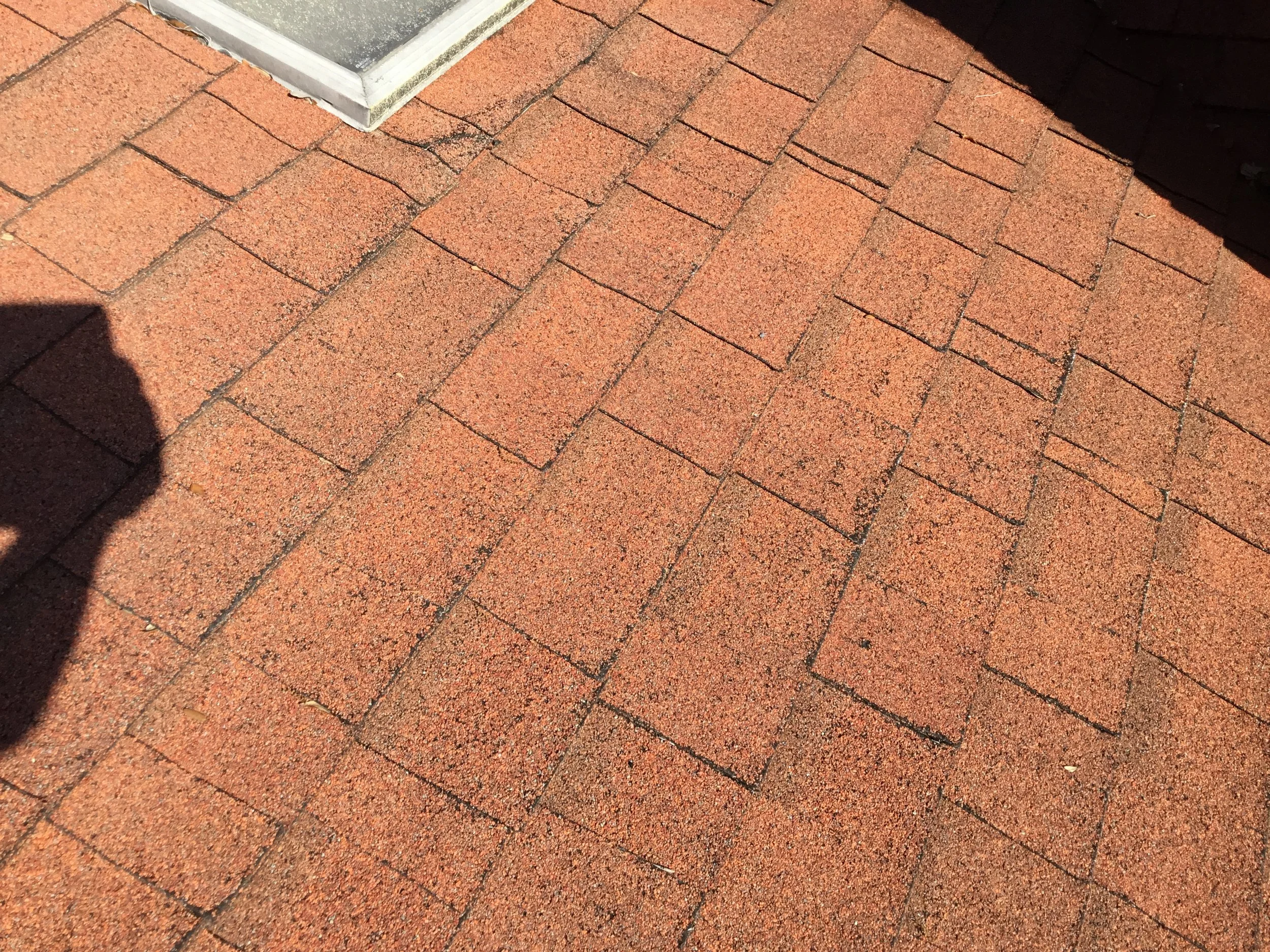 Section of an asphalt shingle roof with visible storm-related damage, including displaced and worn shingles across an exposed plane. When damage appears in this pattern, it often signals broader vulnerability to leaks — making professional inspection