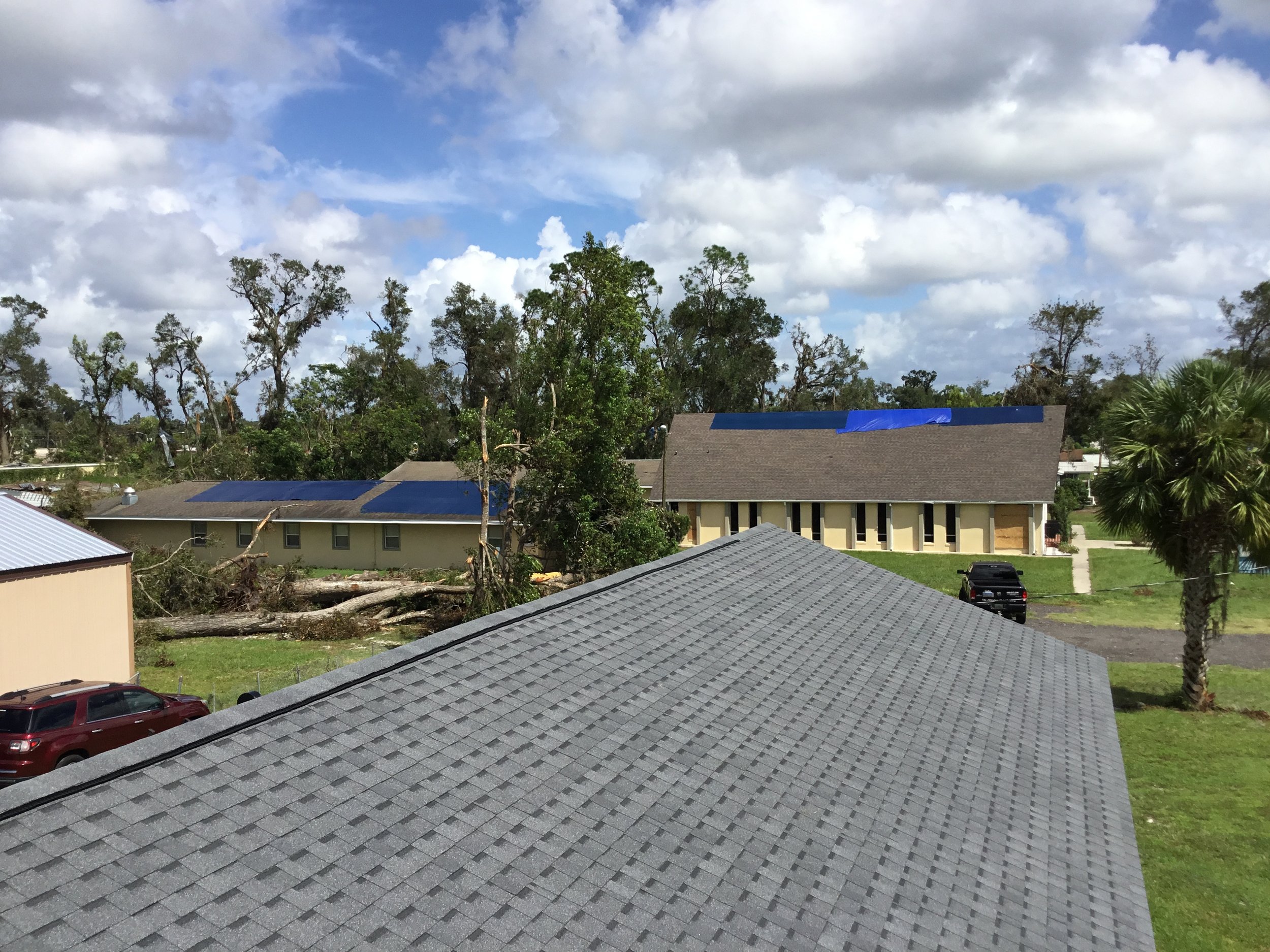 View from one of our newly replaced roofs that stood directly in a recent tornado’s path — yet sustained zero damage. In the distance, you can see storm impact on a nearby church roof, underscoring why proper materials, fastening, and installation ma