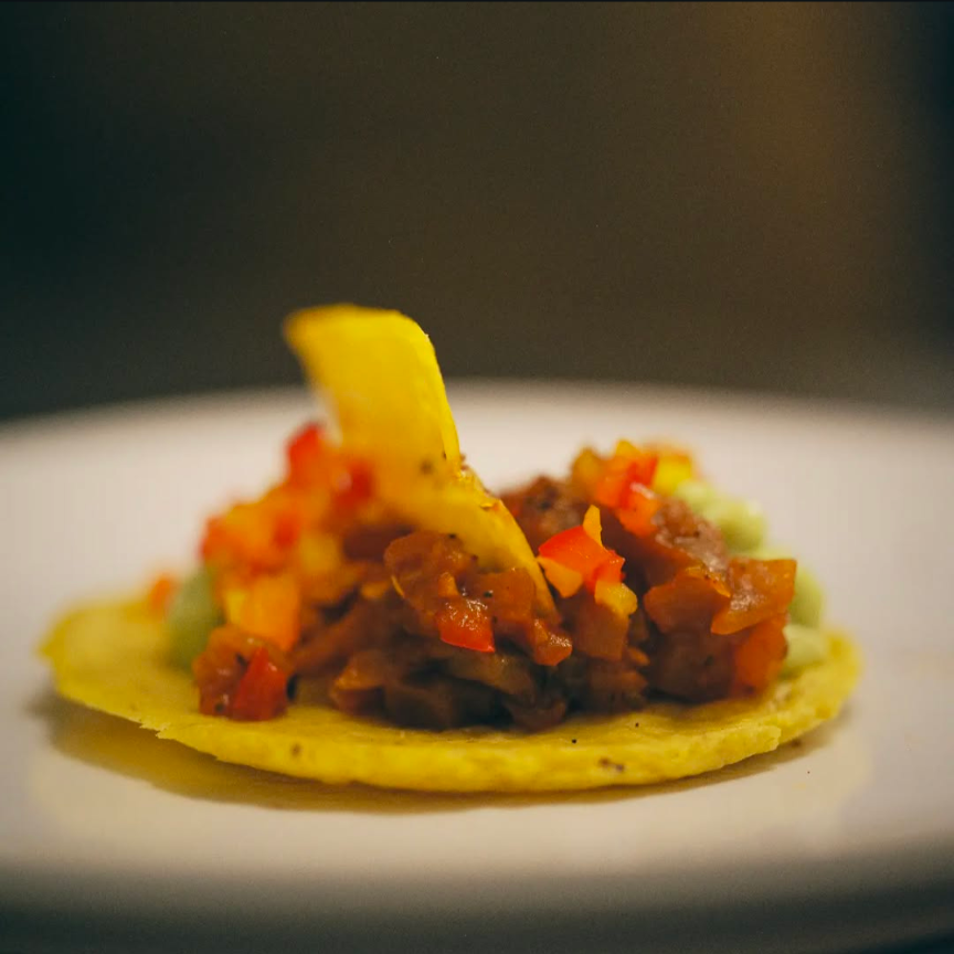 Close-up of a taco with seasoned meat and diced vegetables on a flat tortilla