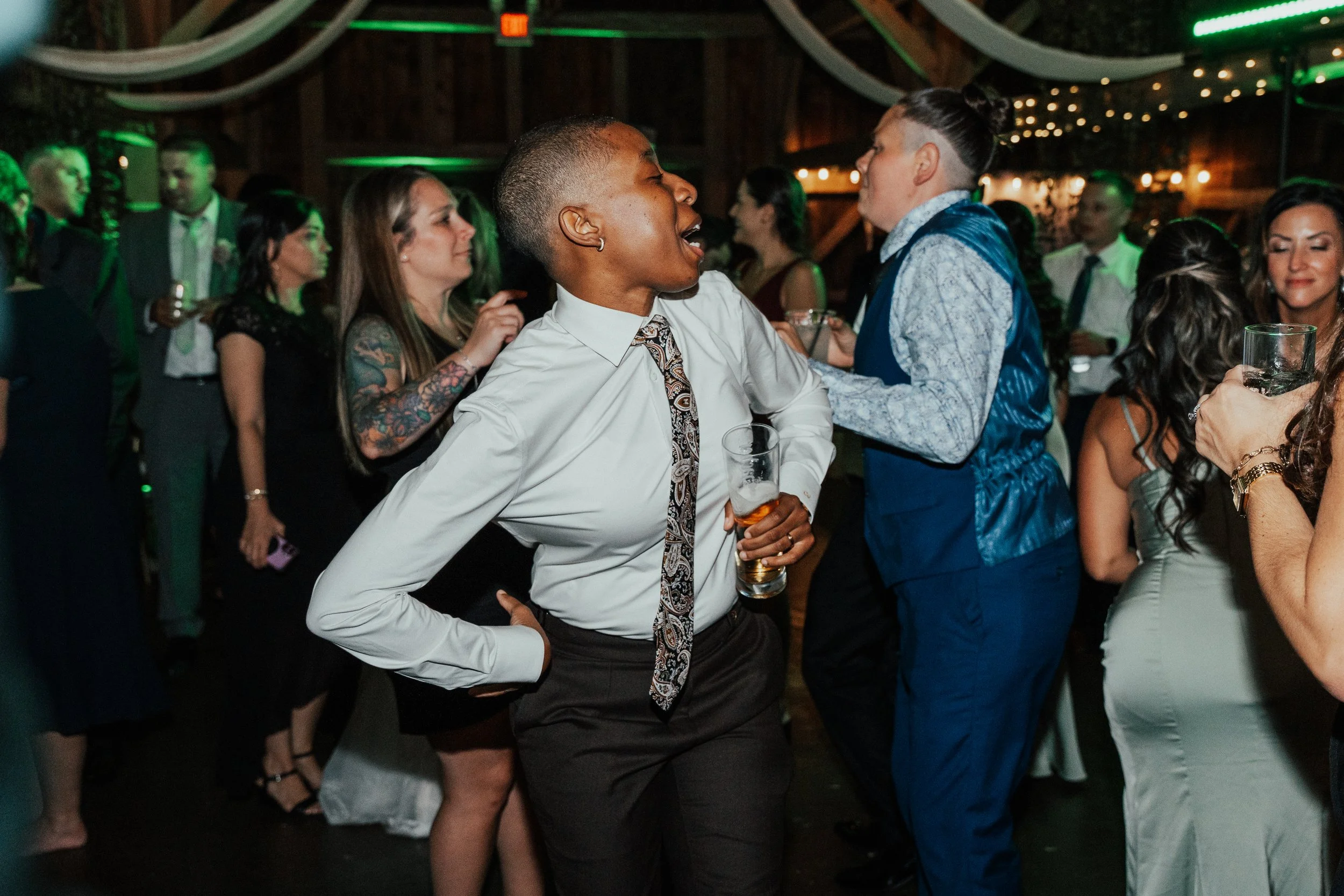 People dancing and socializing at a lively indoor event or party with green and yellow lighting.